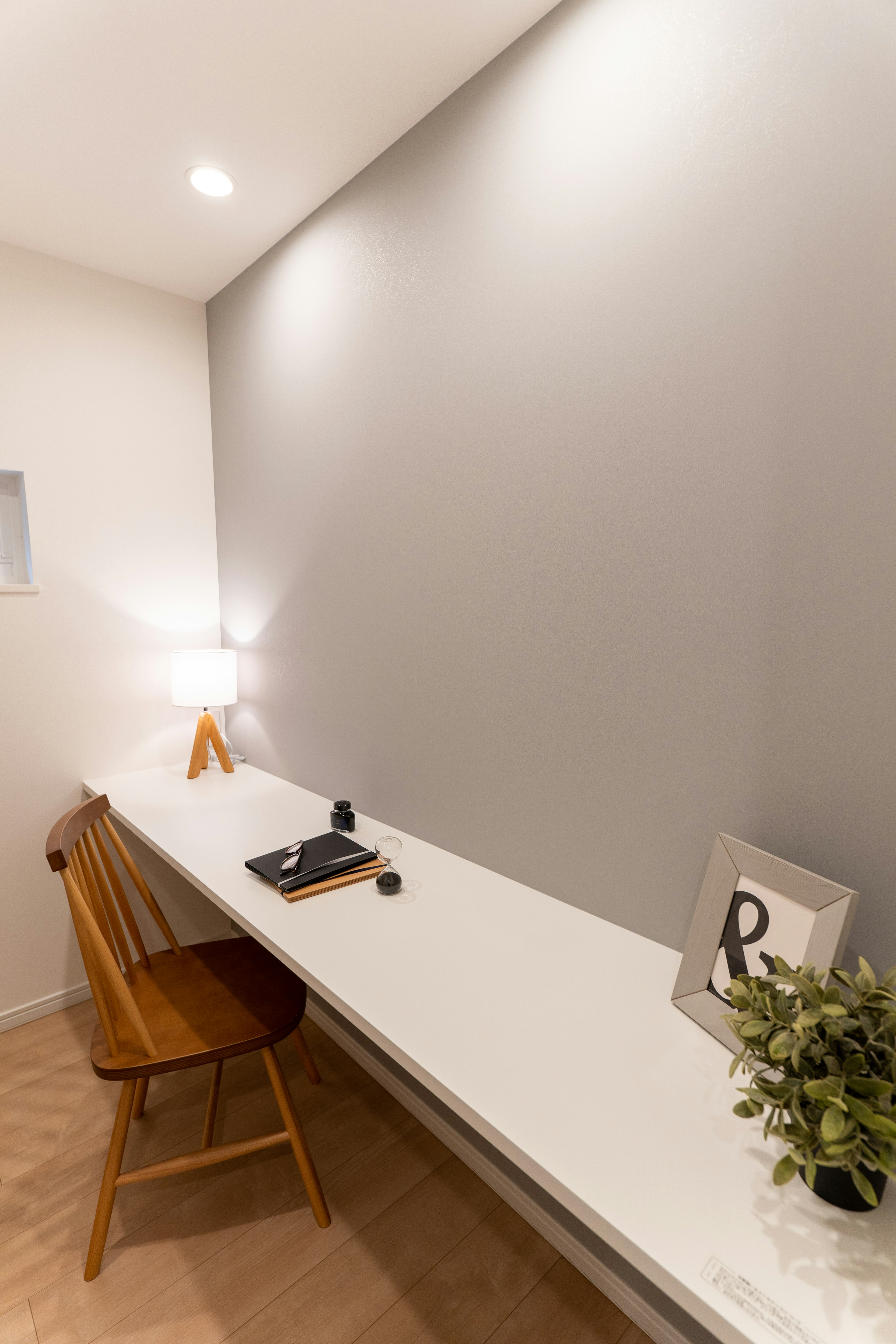 Minimalist workspace featuring a white desk and a wooden chair with decorative items