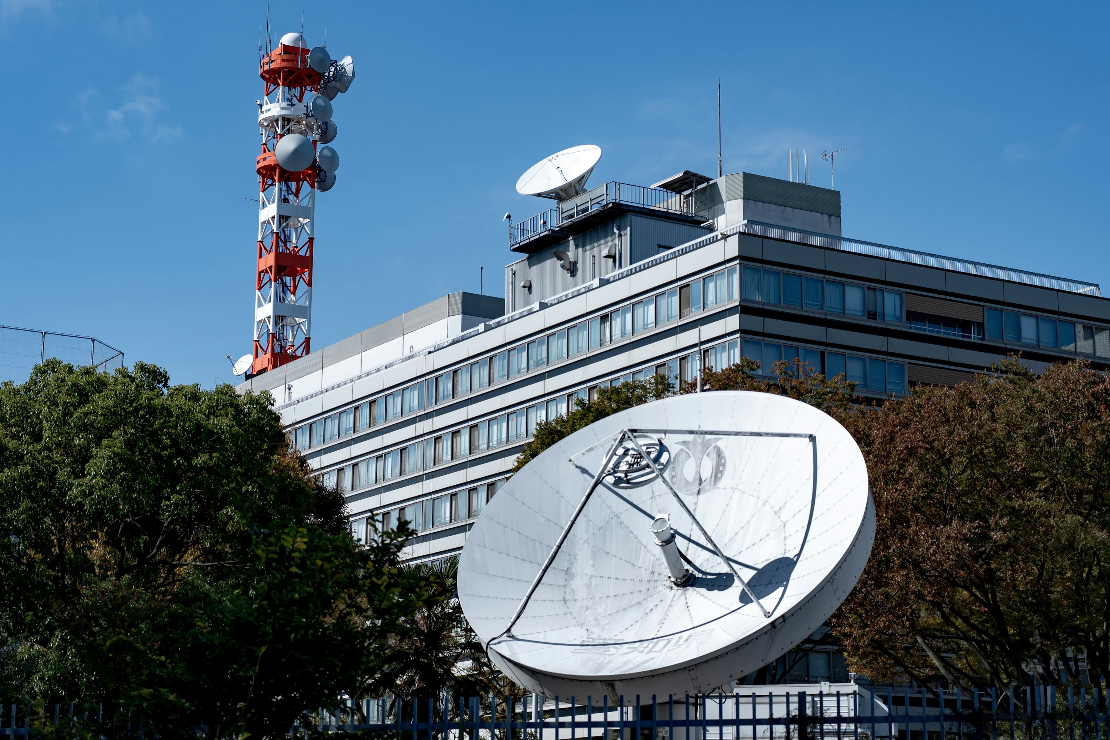 Eksterior bangunan dengan antena satelit dan menara komunikasi