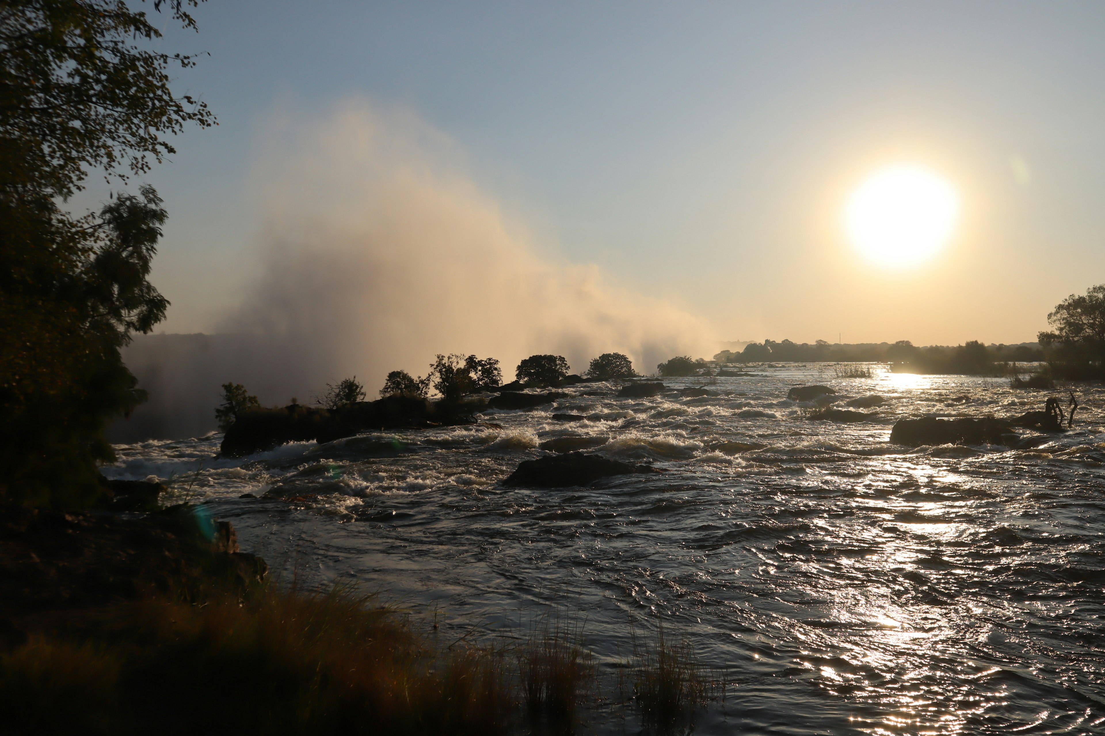 Vista escénica de un río con un atardecer resplandeciente y niebla