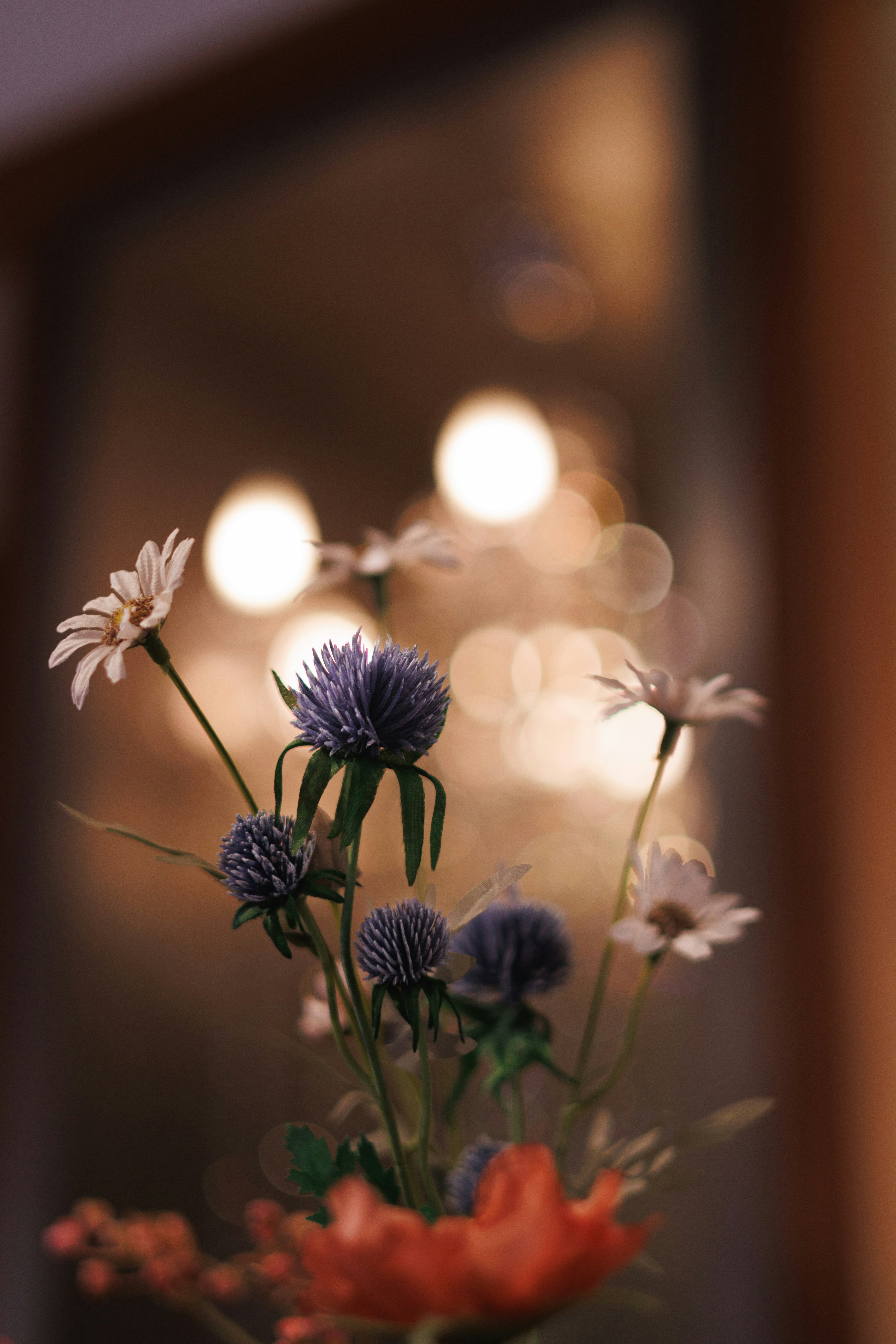 Un bouquet de fleurs variées dans un vase avec des lumières floues en arrière-plan