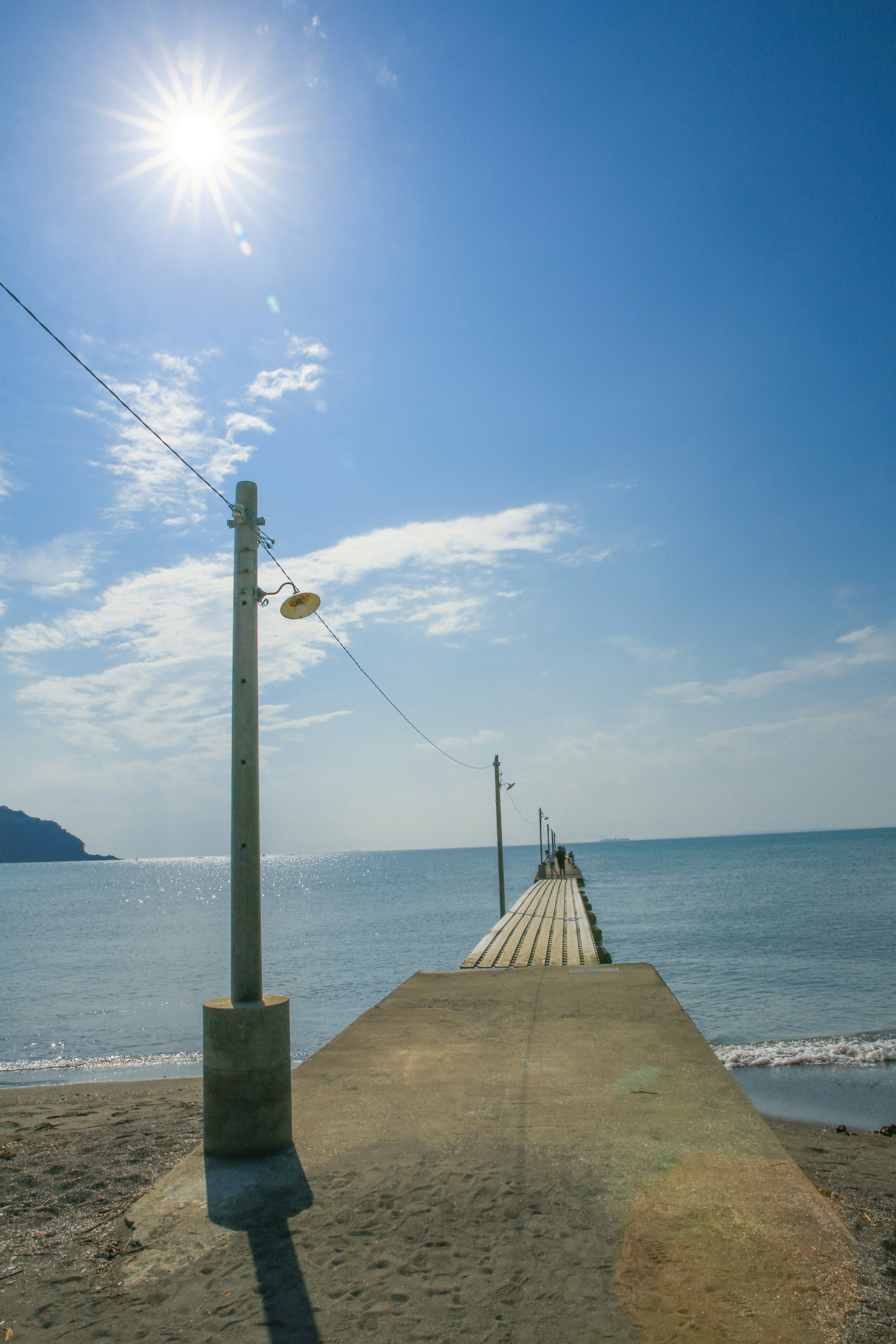 Scenic view of a pier extending into the blue sea under a bright sun