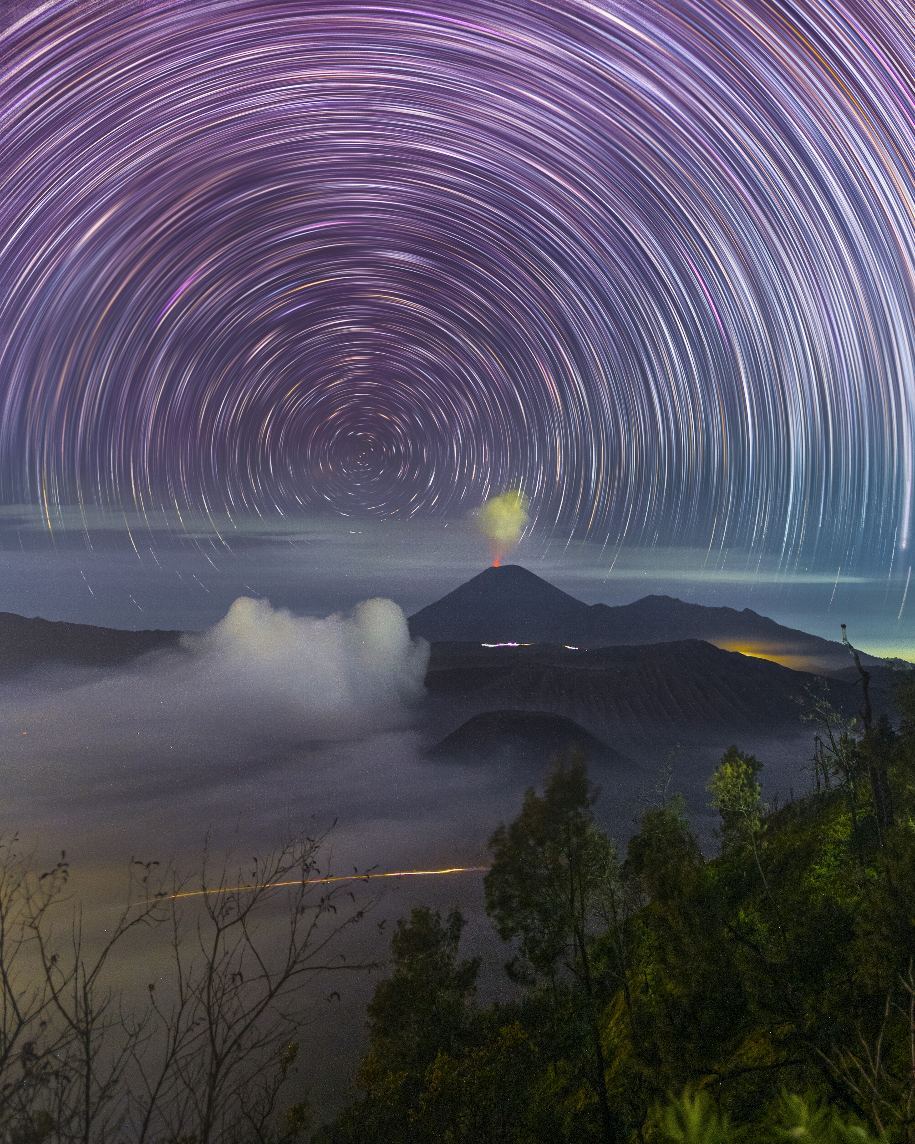 星の軌跡が描かれた美しい夜空と雲に覆われた山の風景