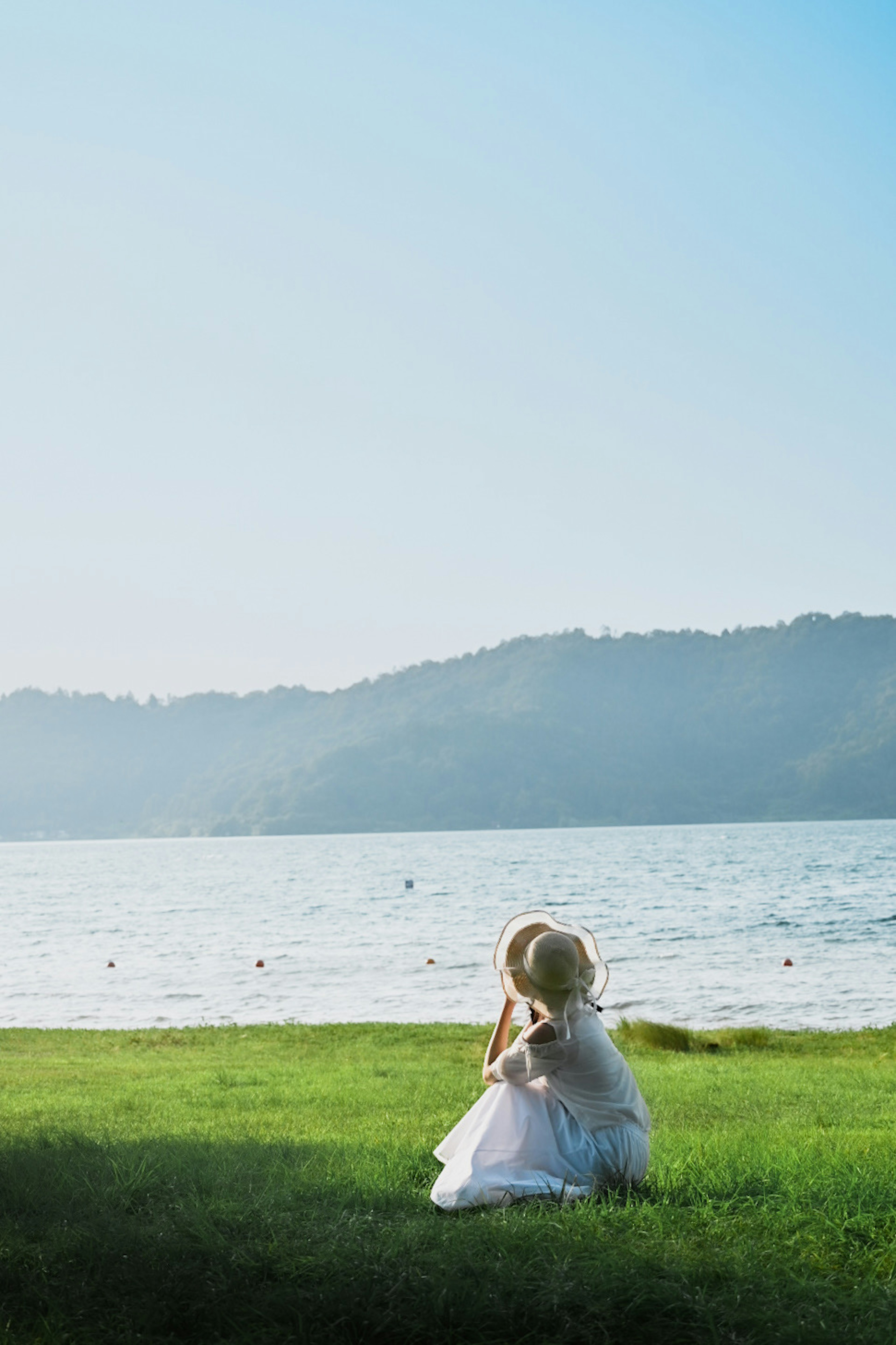 Una niña sentada en la hierba junto al lago con una vista escénica