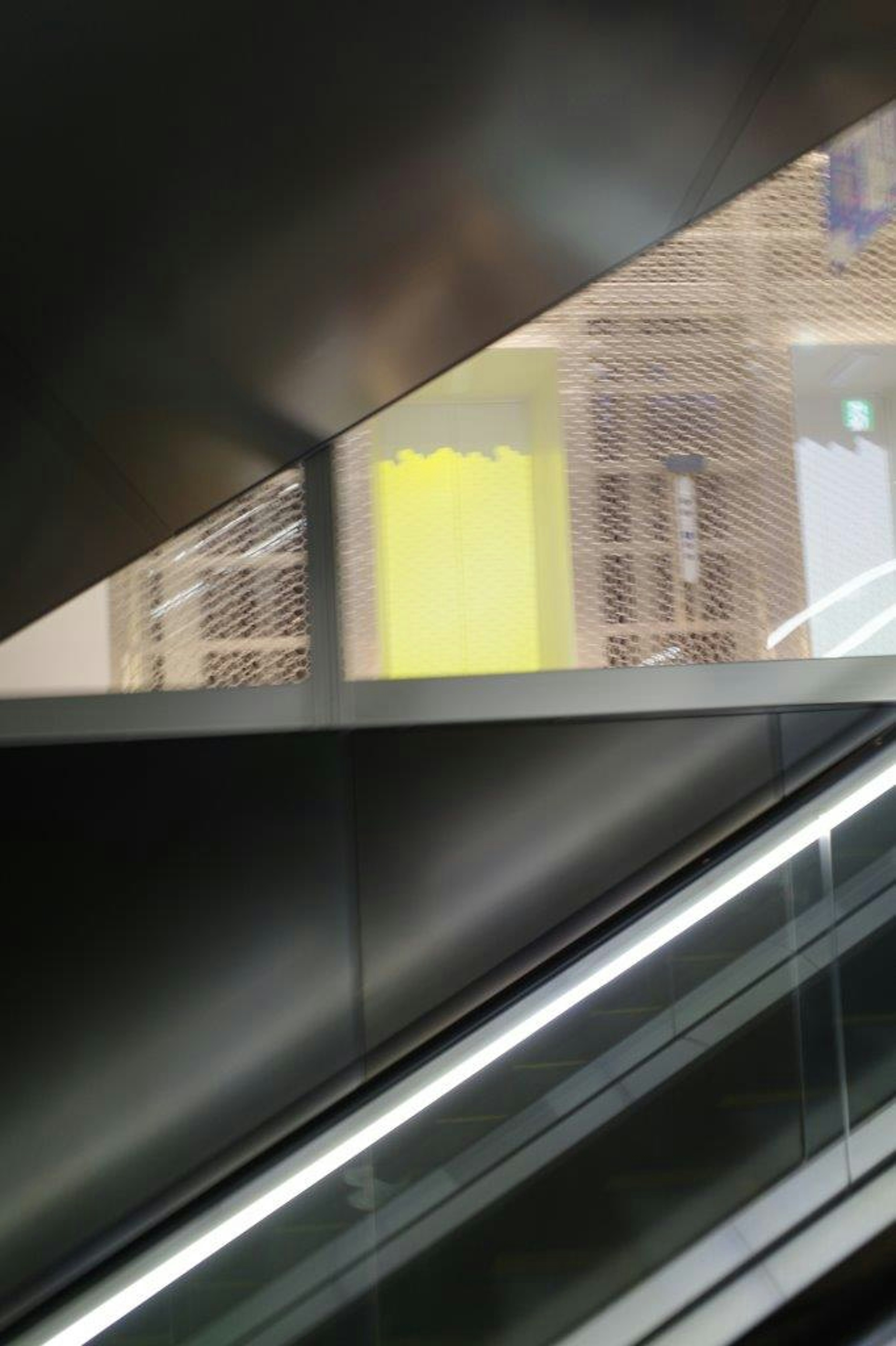 Vista desde una escalera mecánica con una pared amarilla brillante