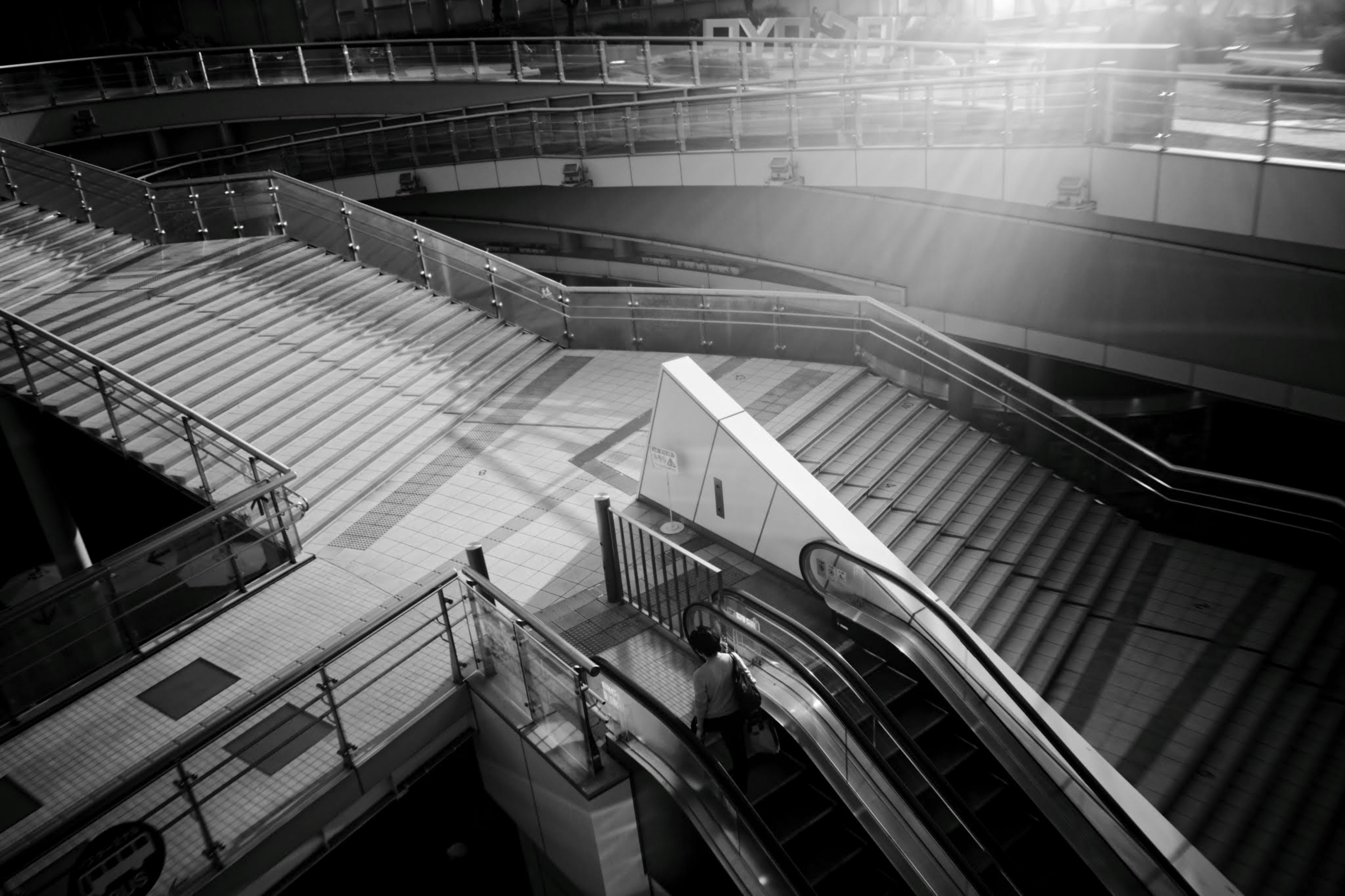 Black and white photo of a modern space with intersecting stairs and escalators