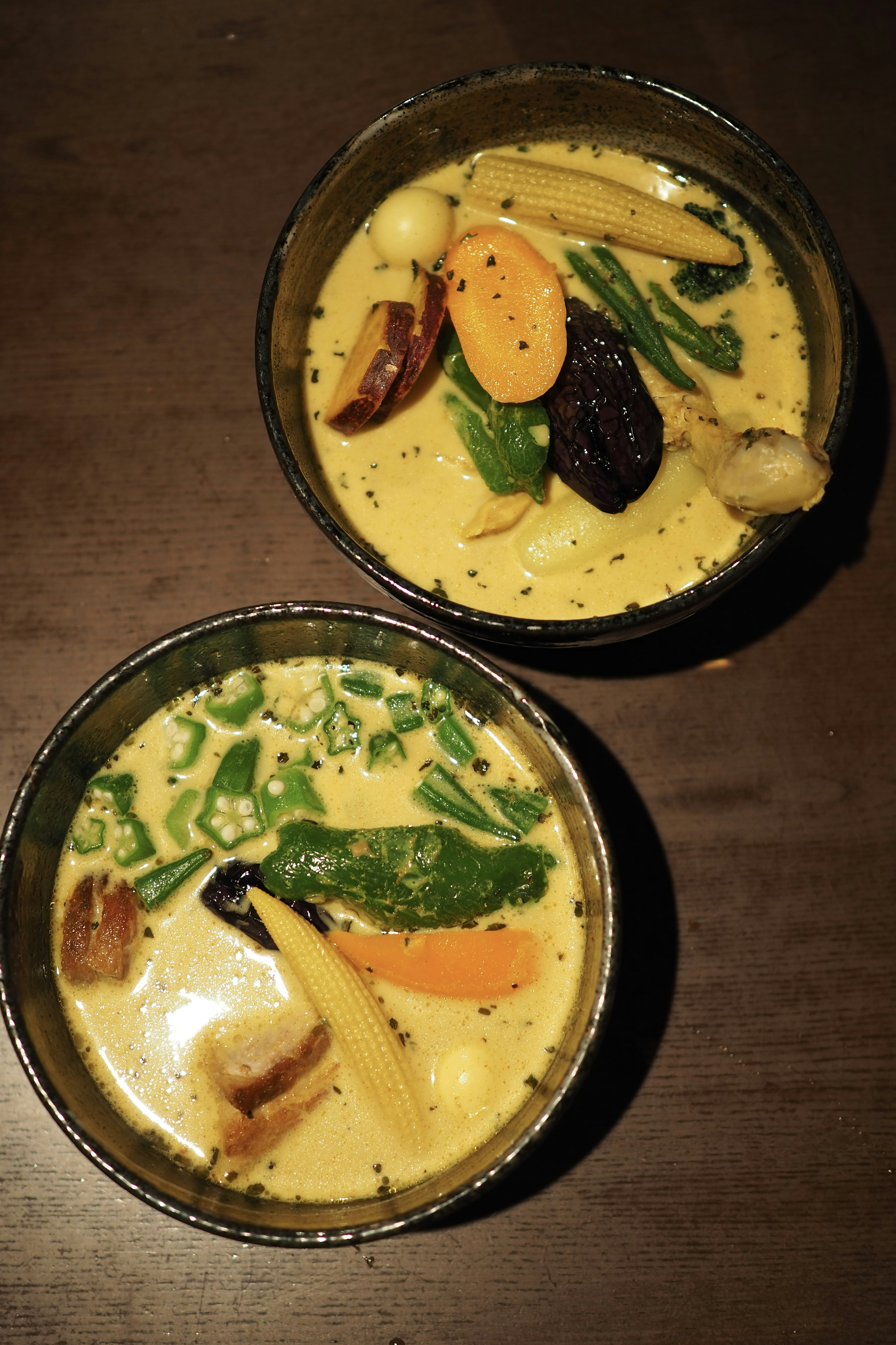 Dos tazones de sopa con sabor a curry llenos de verduras coloridas