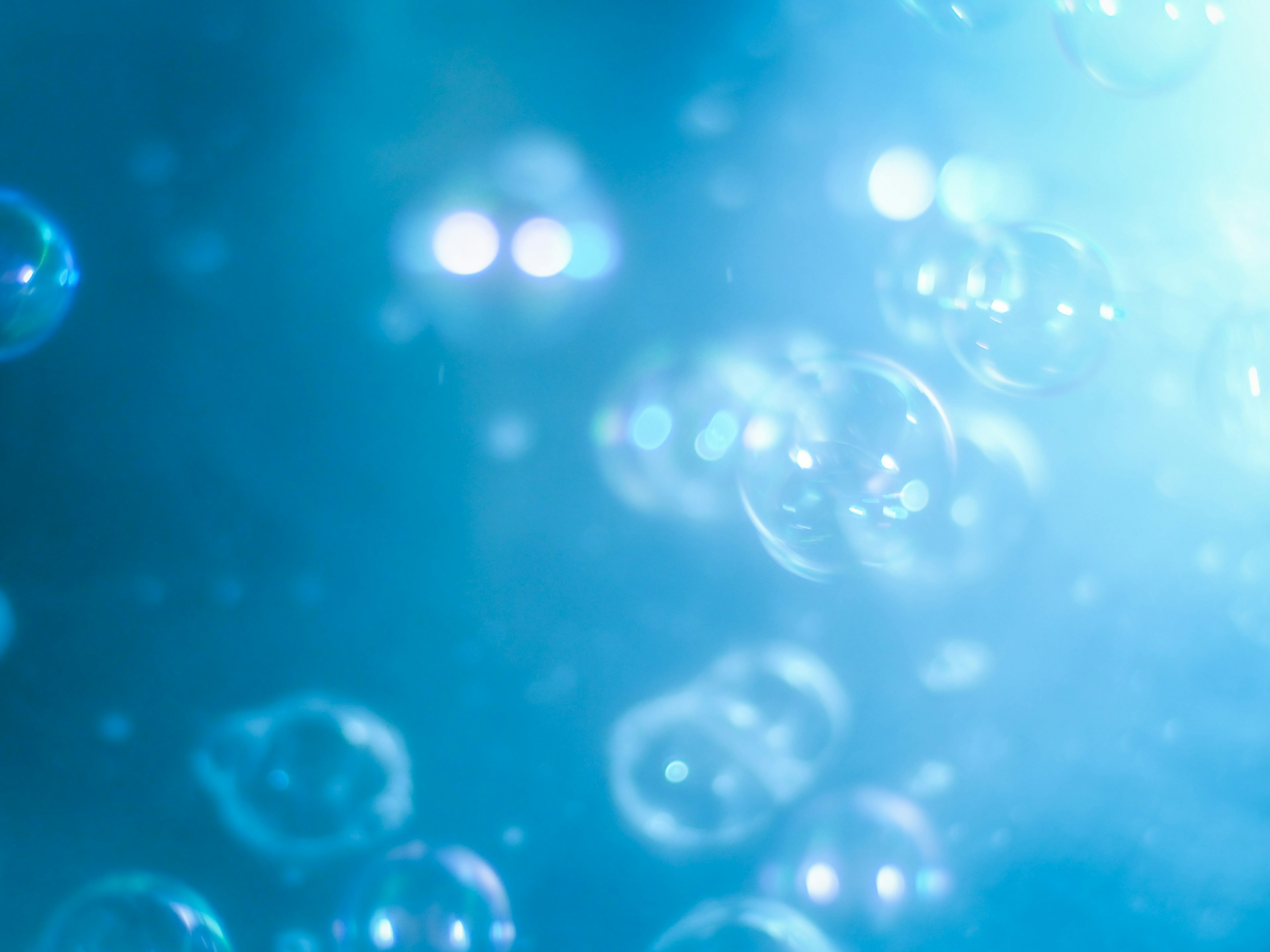 Primer plano de burbujas flotando en un fondo azul con hermosos reflejos de luz