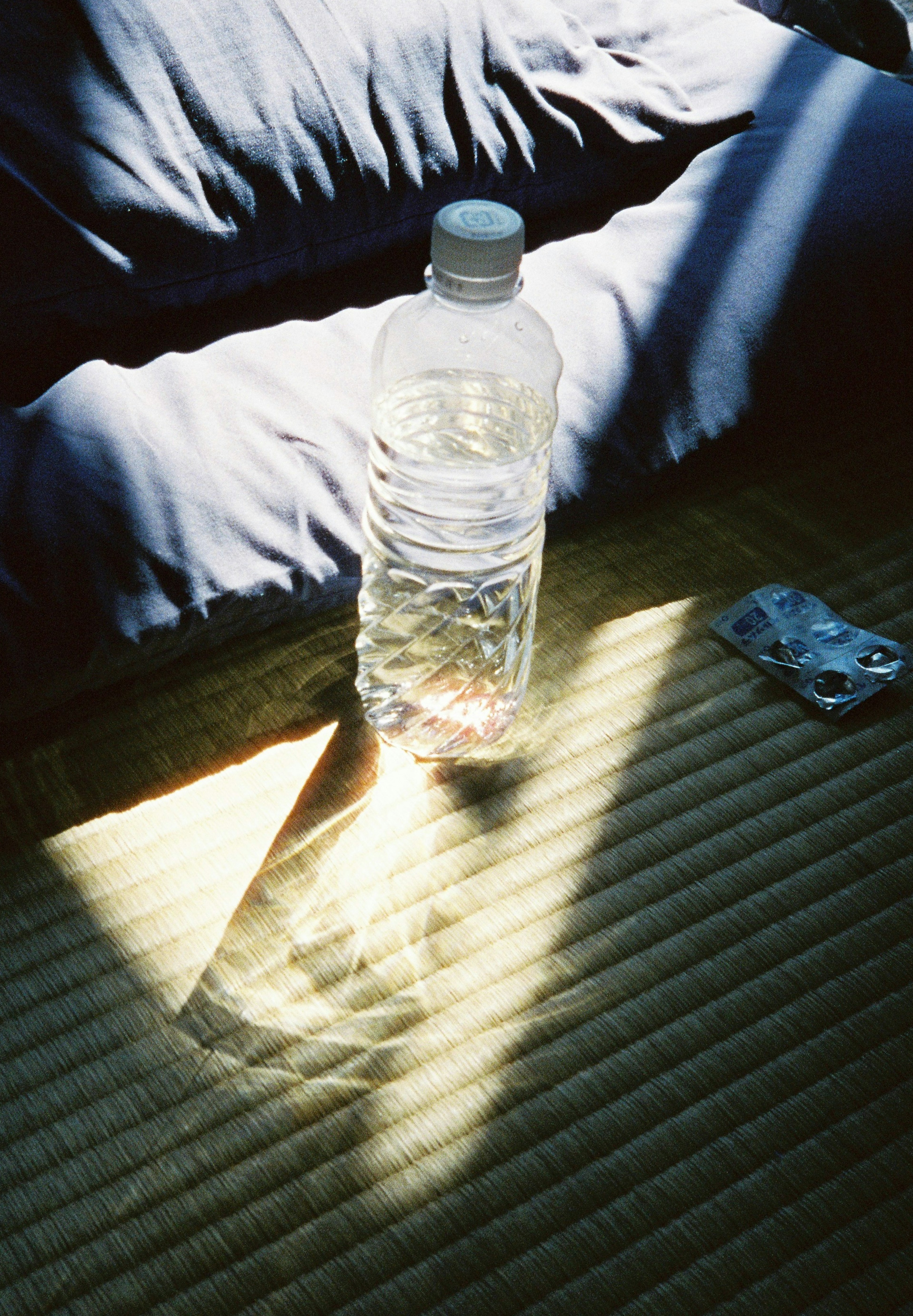 A water bottle placed on tatami flooring illuminated by soft light