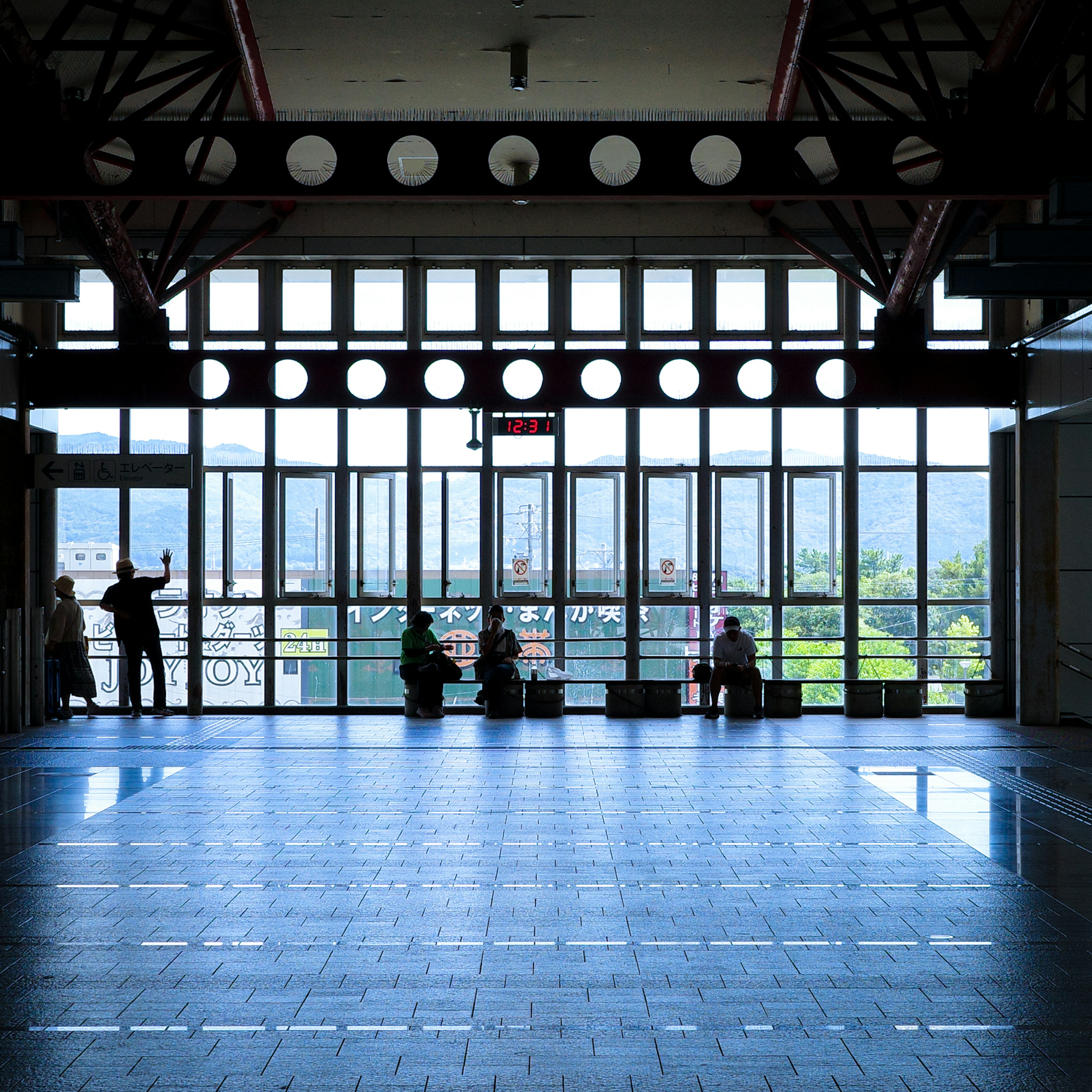 明るい空間に人々が座っている広いロビーの風景