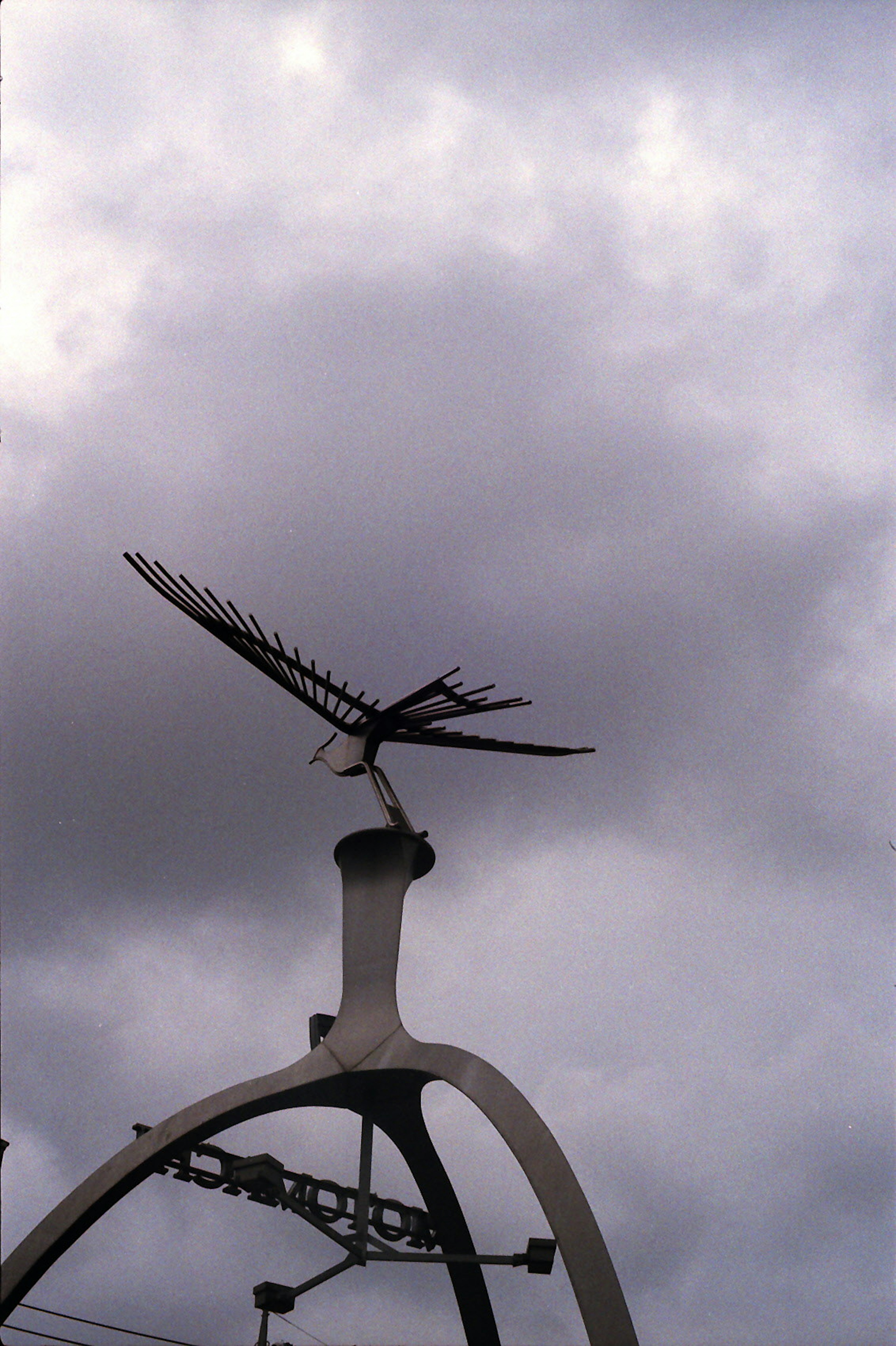 Bird sculpture soaring towards the sky with gray clouds