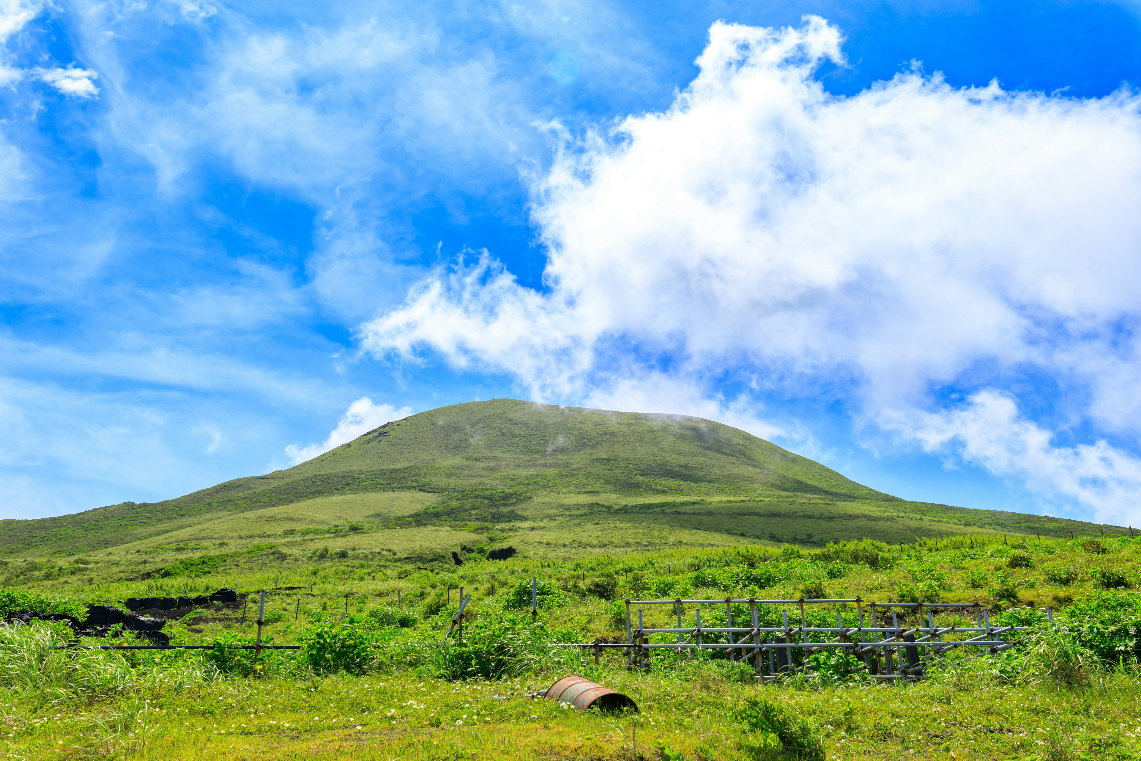 Vue pittoresque d'une colline verte sous un ciel bleu avec des nuages blancs