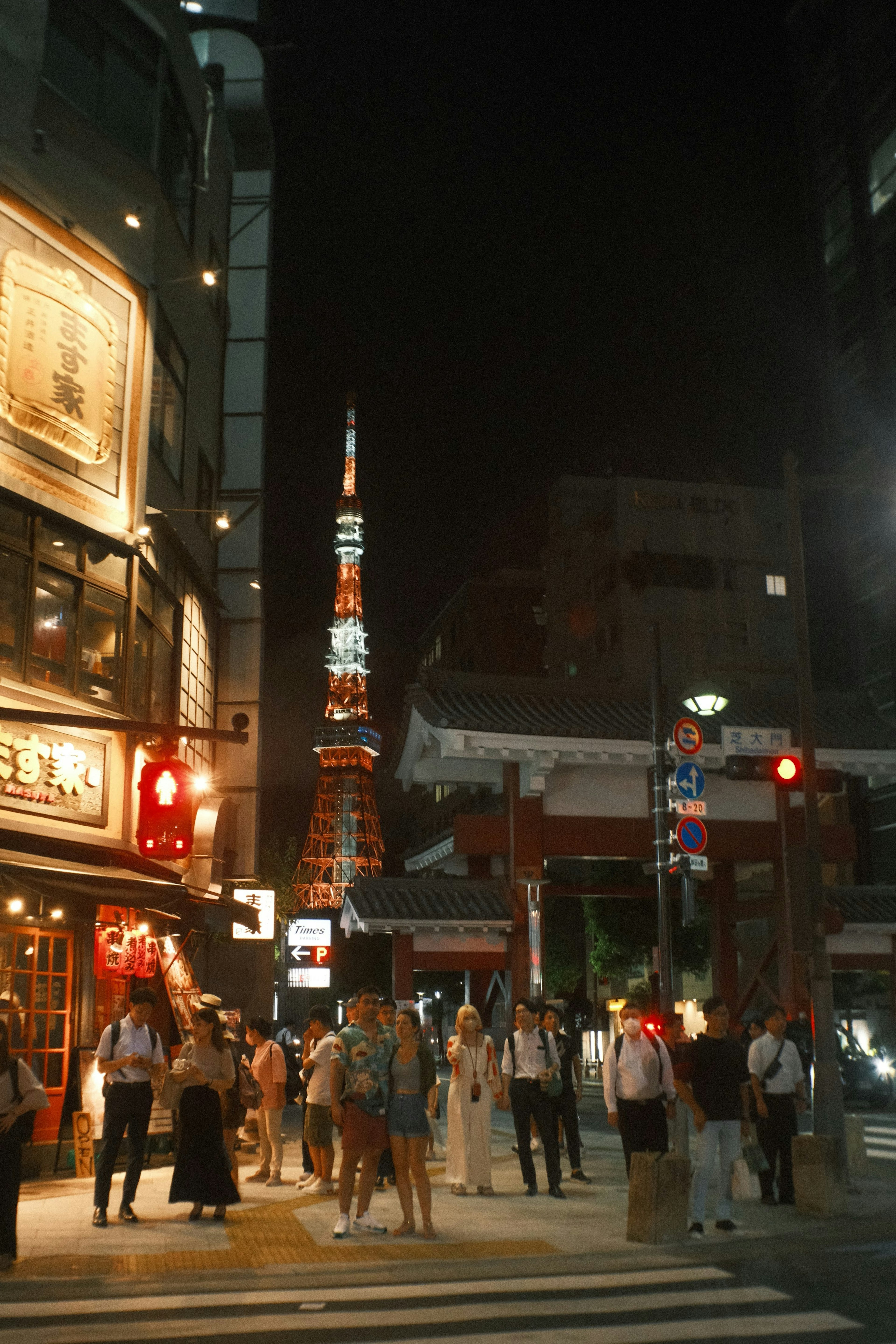 Menschen versammelt vor dem Tokyo Tower bei Nacht mit lebhaften Stadtlichtern