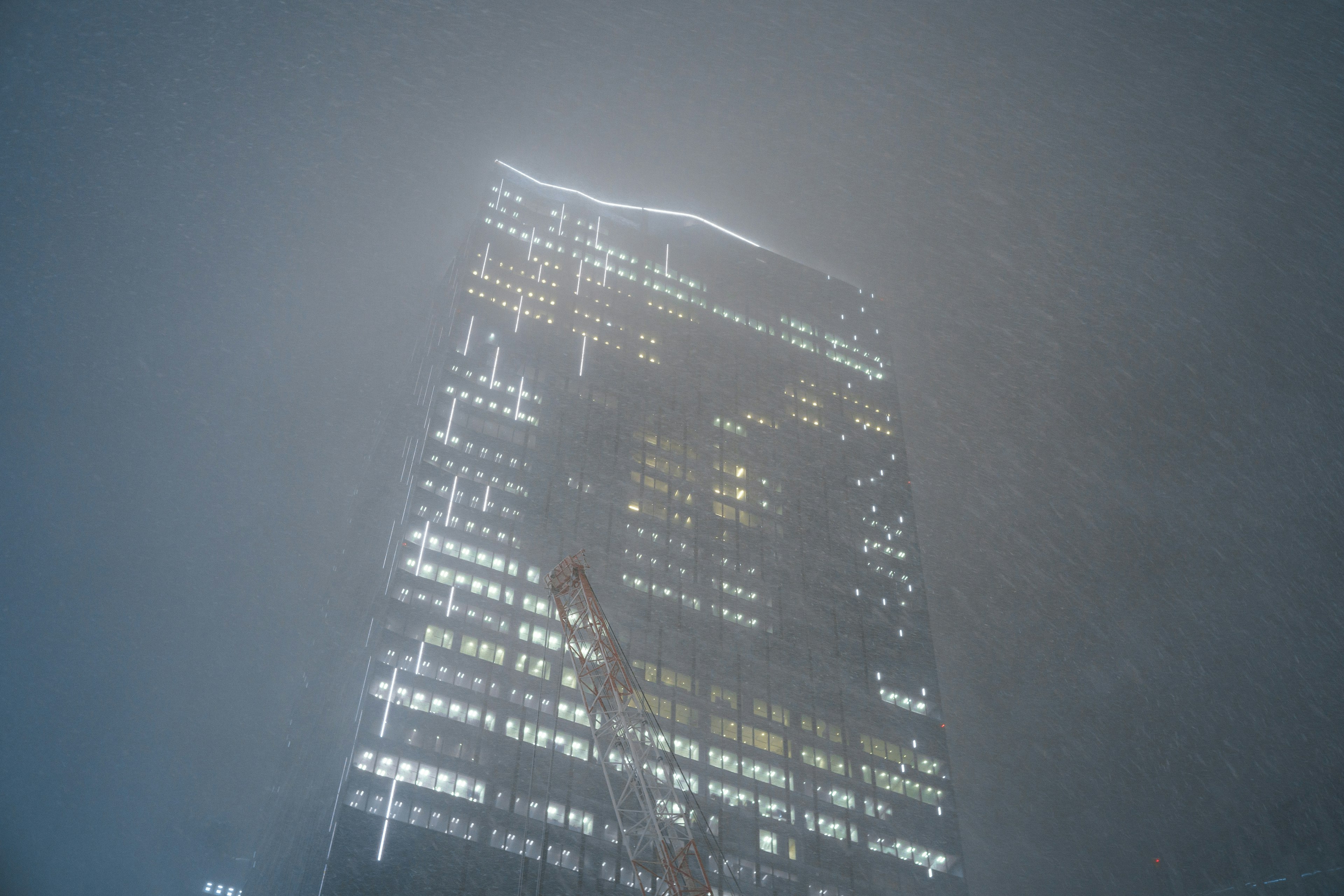 A tall building illuminated through fog with bright windows