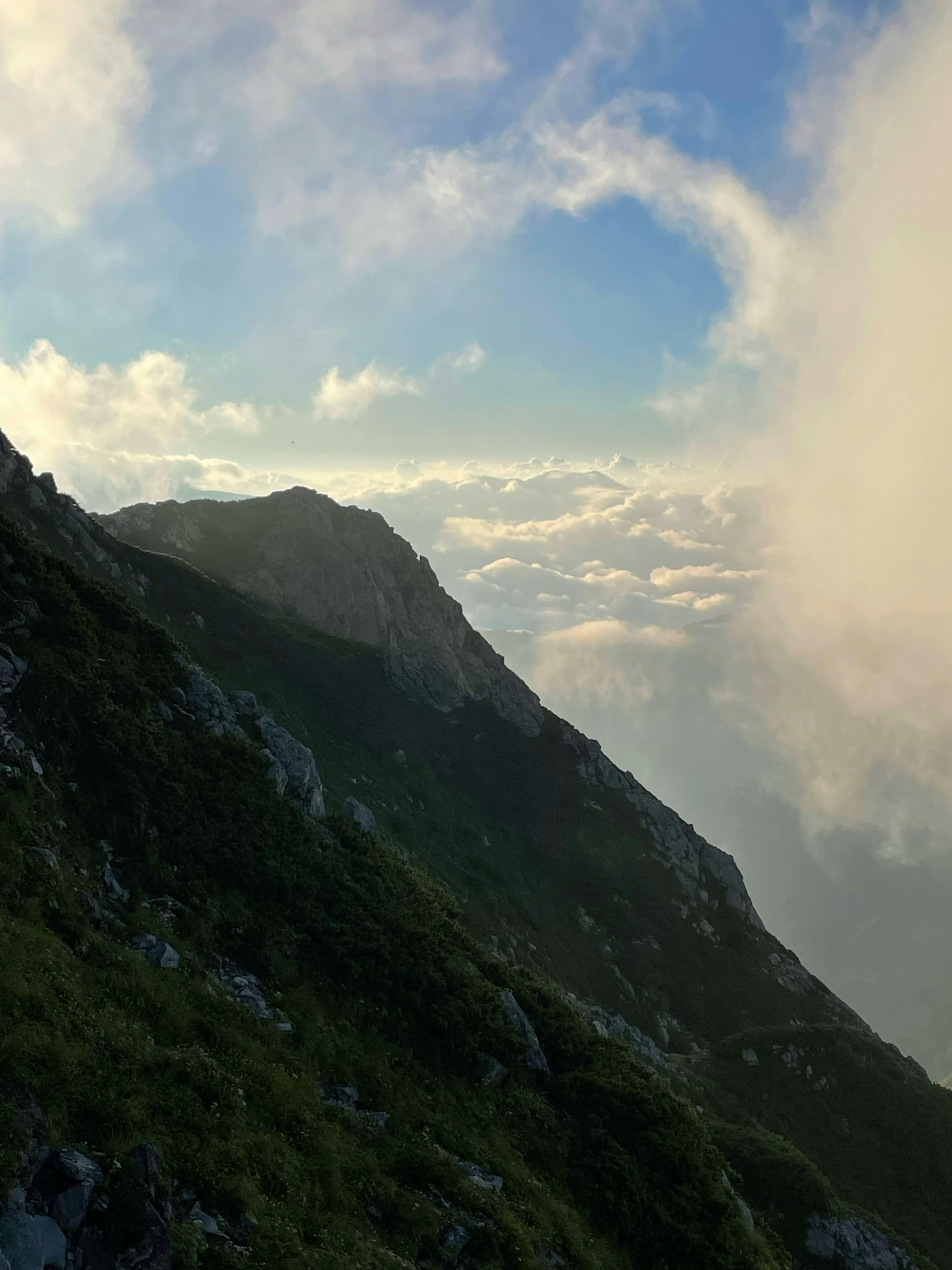 山の斜面と雲が広がる青空の風景