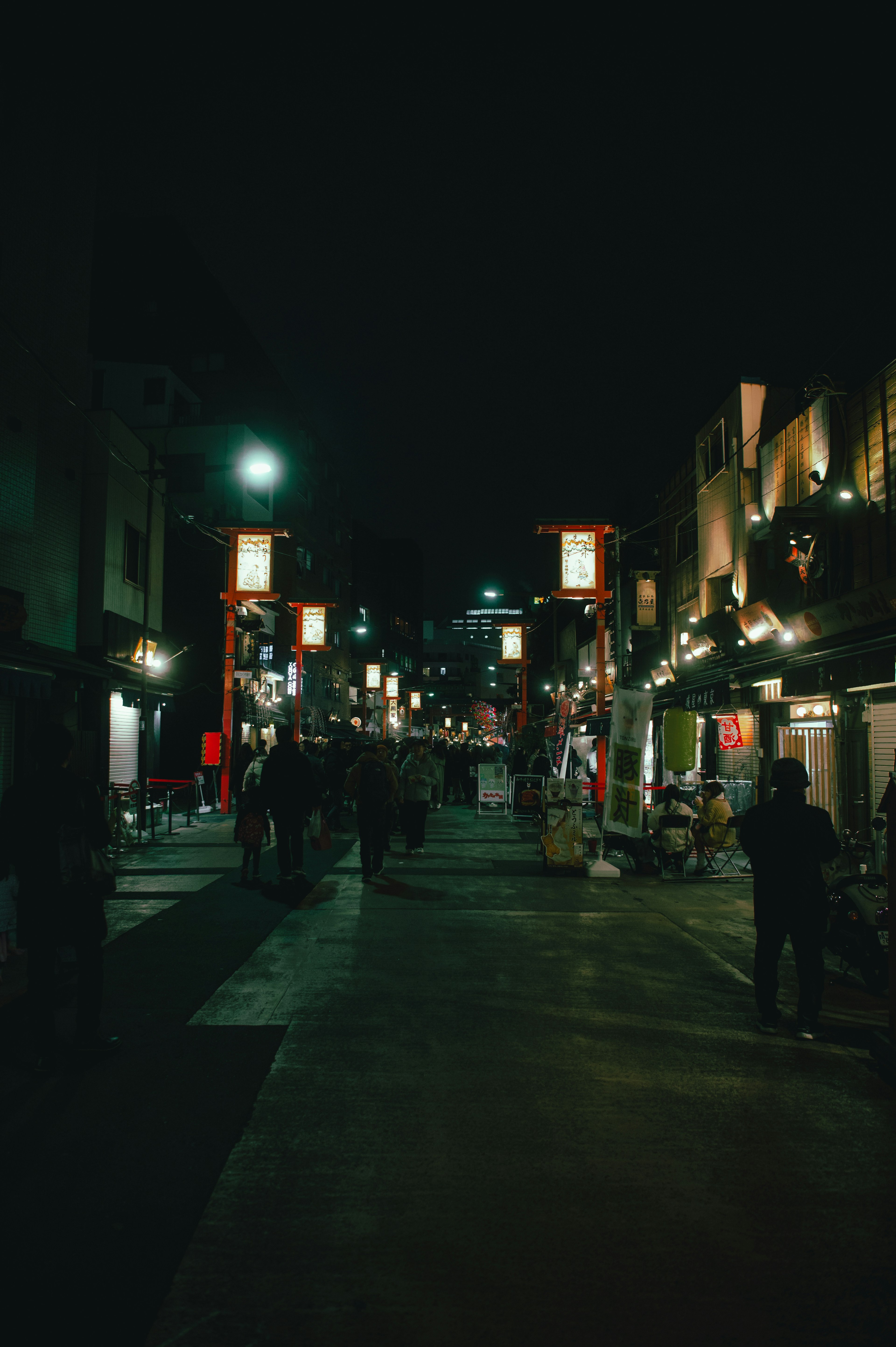 People walking in a night street with illuminated shops and lanterns