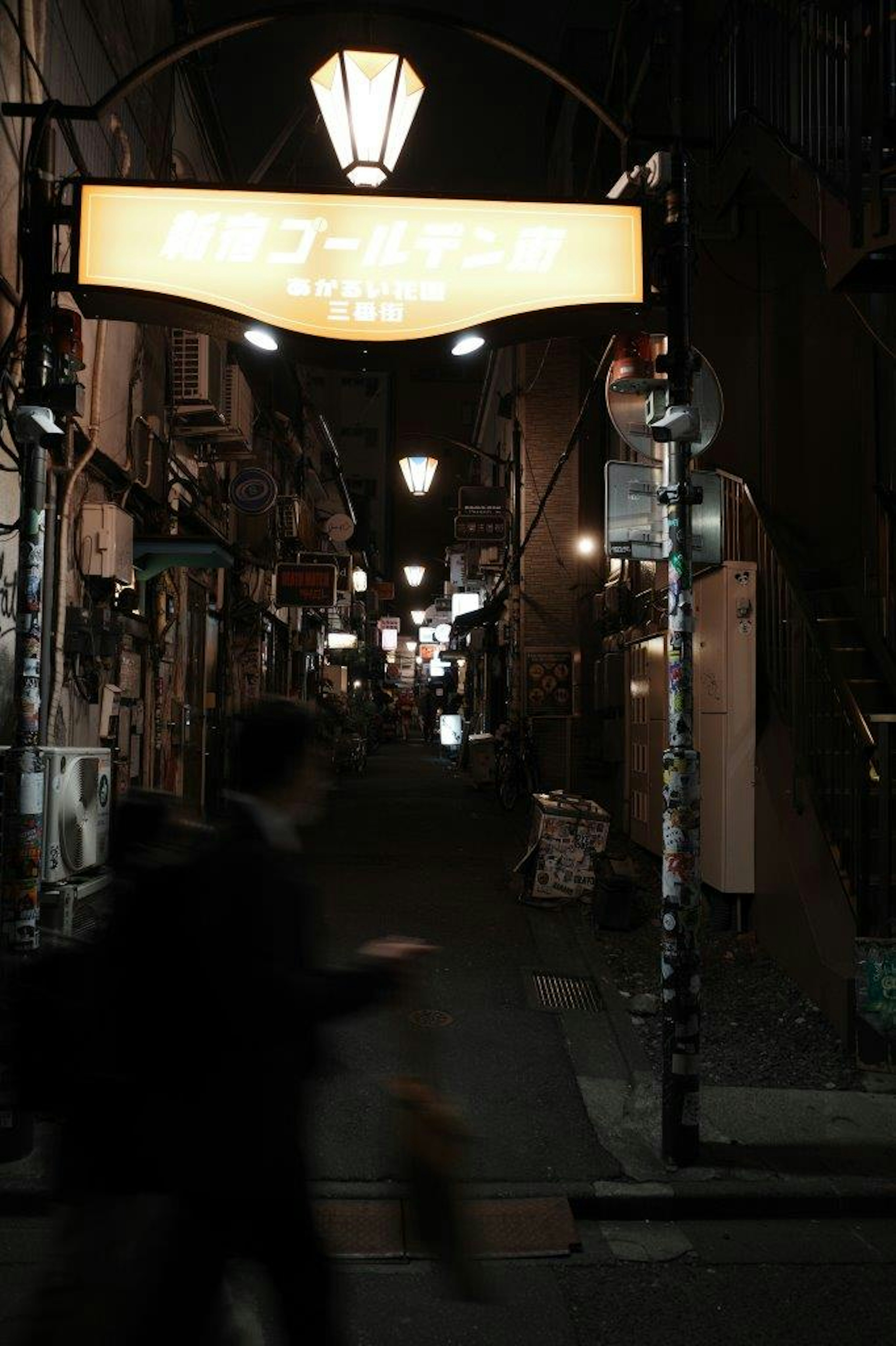 Allée faiblement éclairée avec lampadaires et enseigne