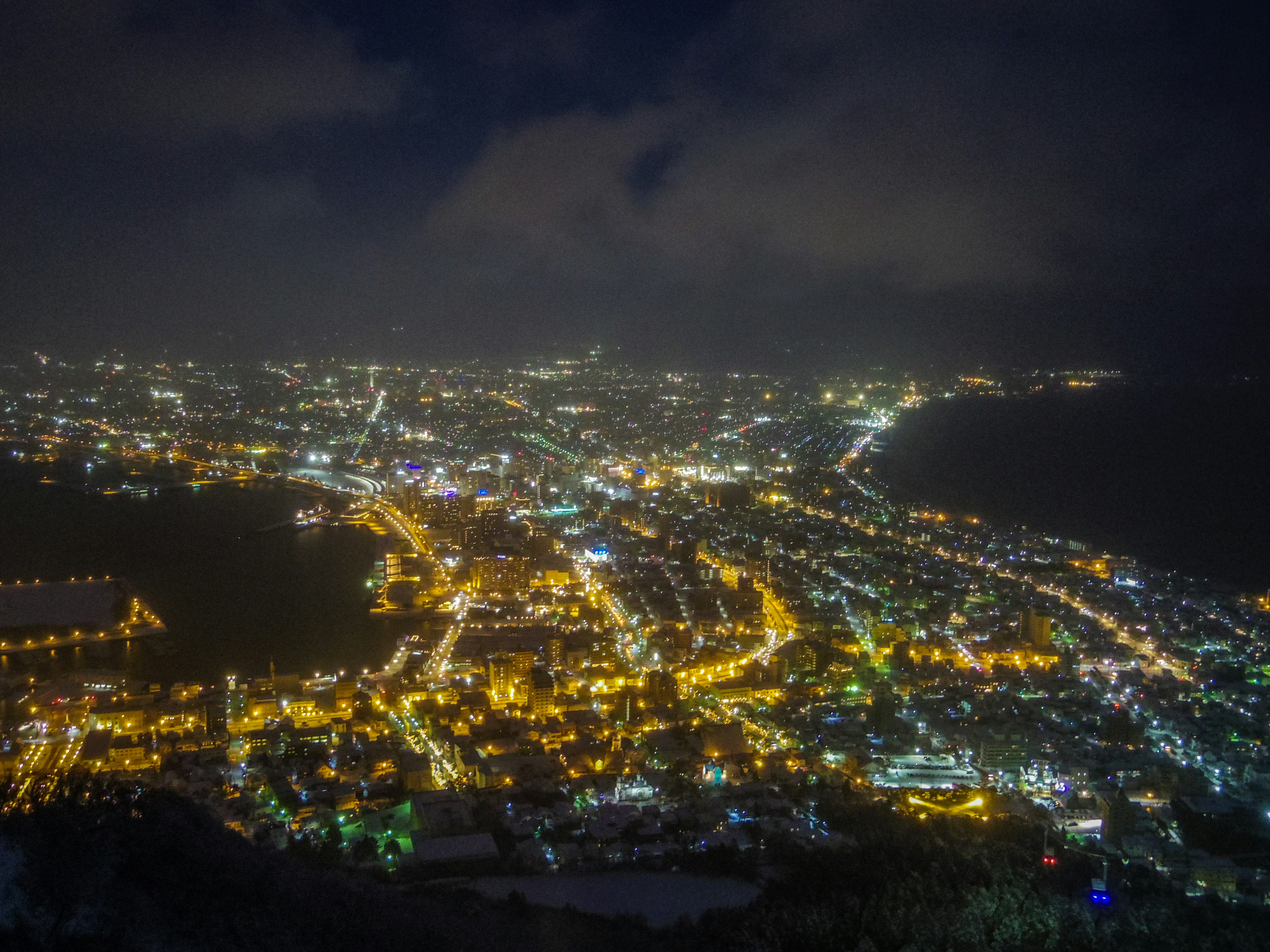 Paisaje urbano nocturno con calles iluminadas y luces del océano