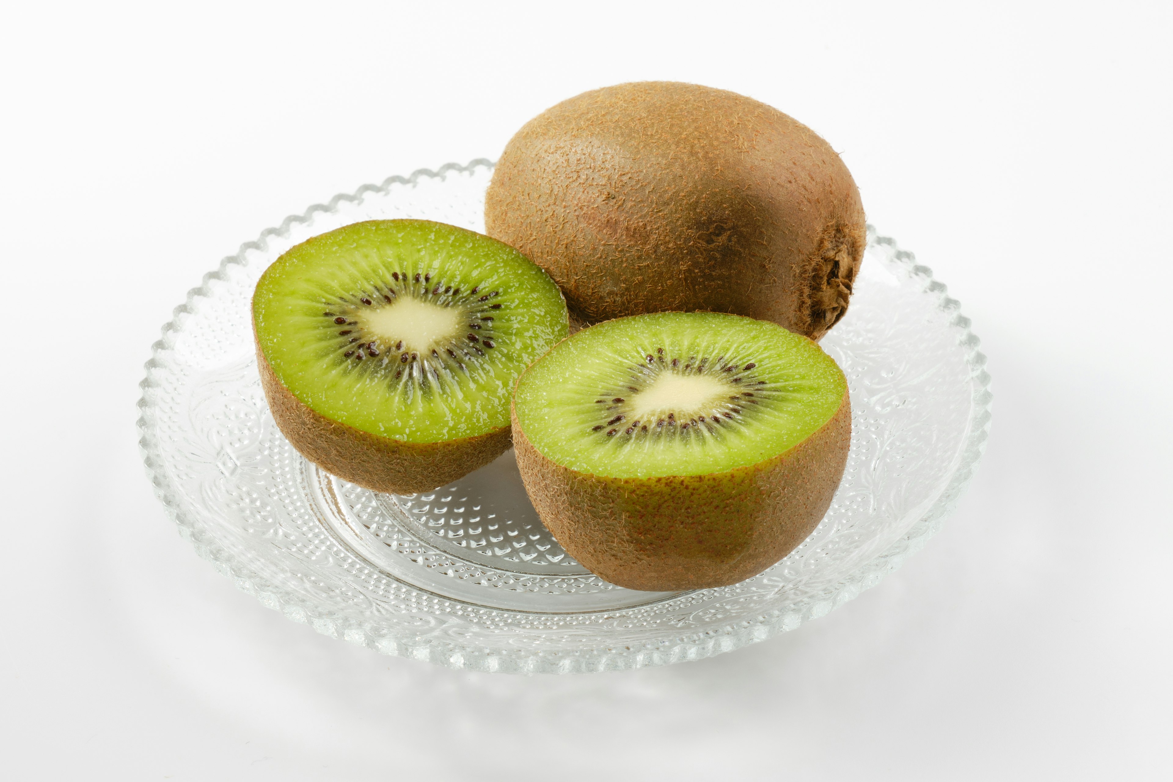 Geschnittene und ganze Kiwi auf einem weißen Teller