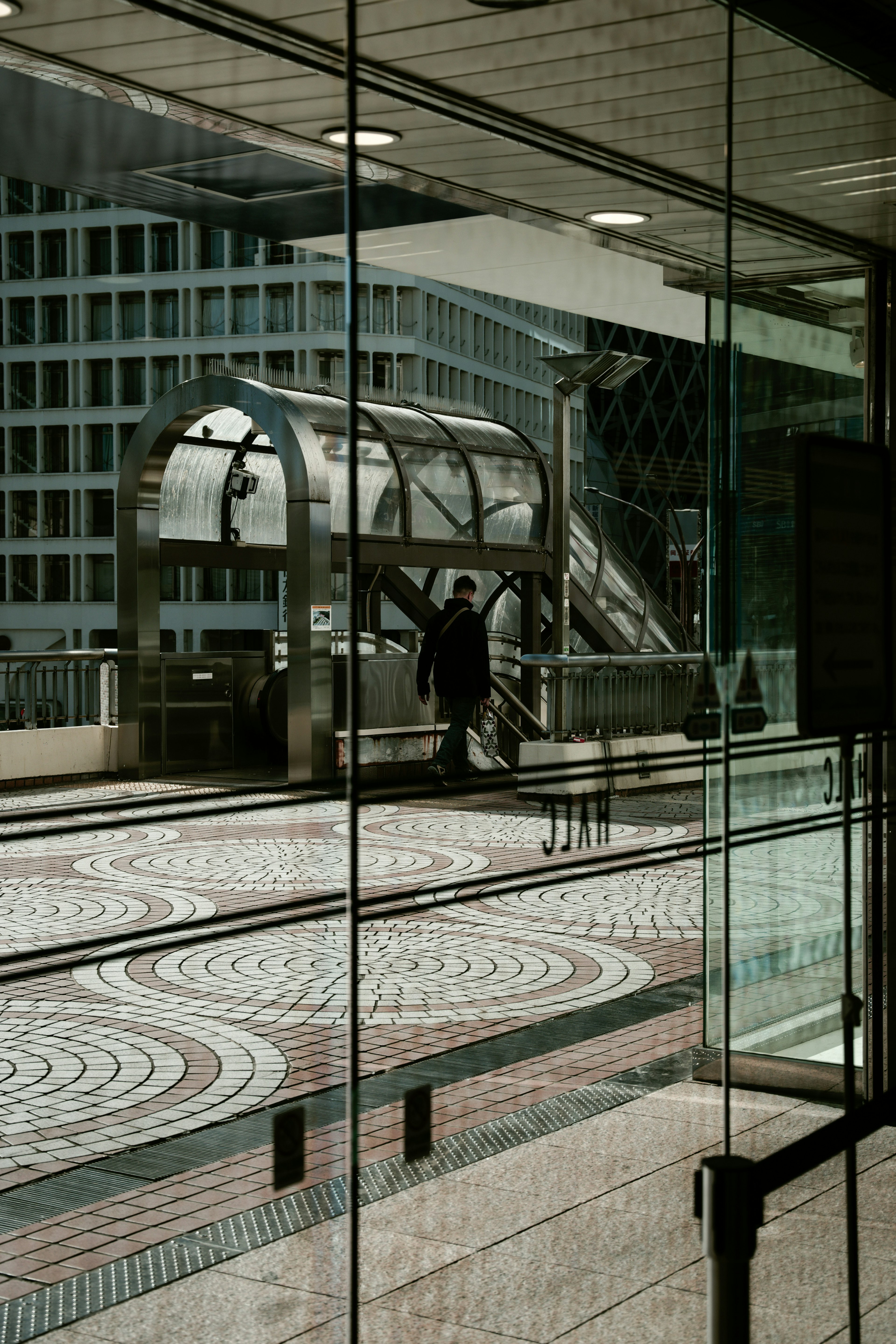 Estación de tren urbana vista a través del vidrio con una escalera mecánica moderna