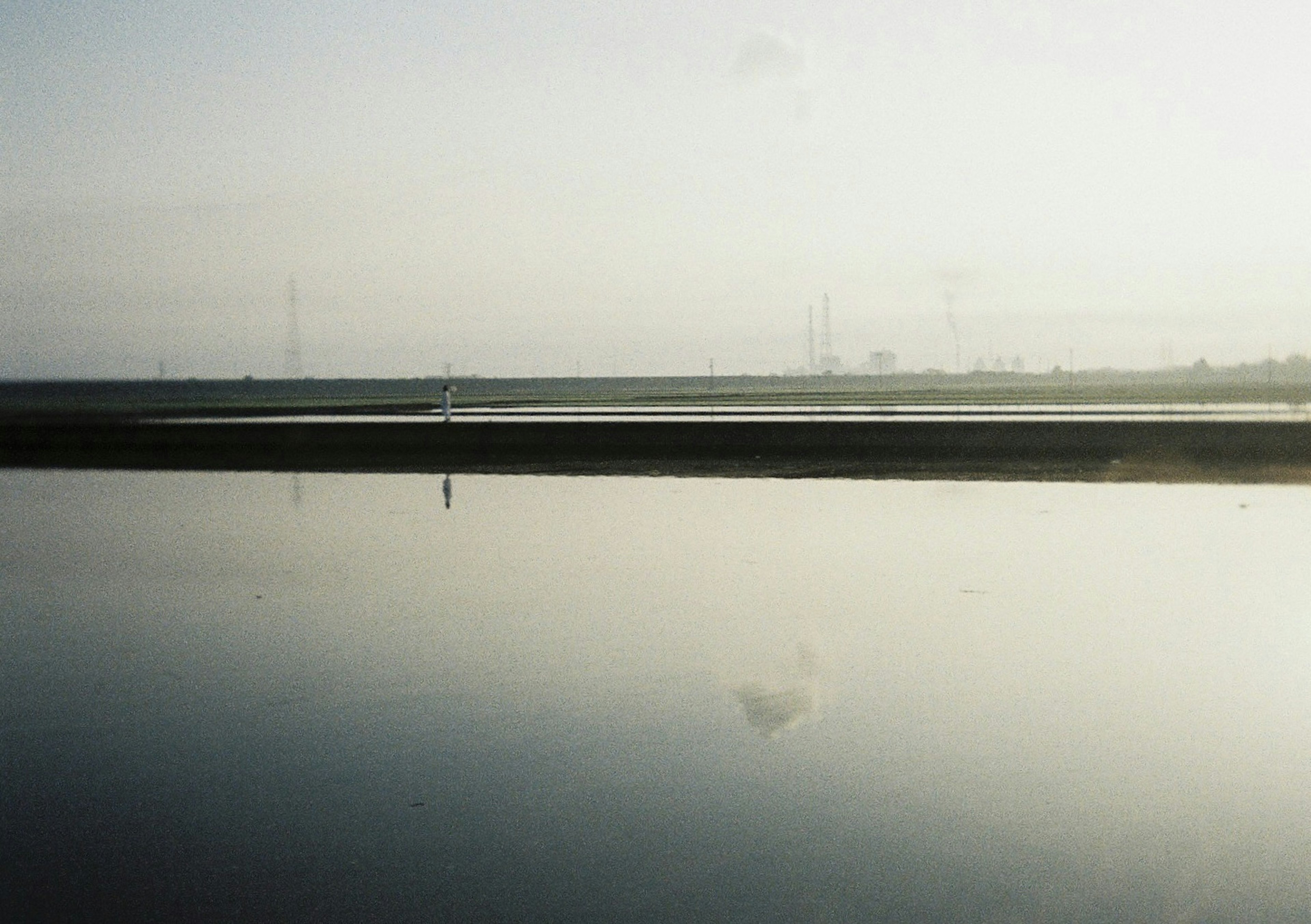 Serene landscape with calm water and distant power lines