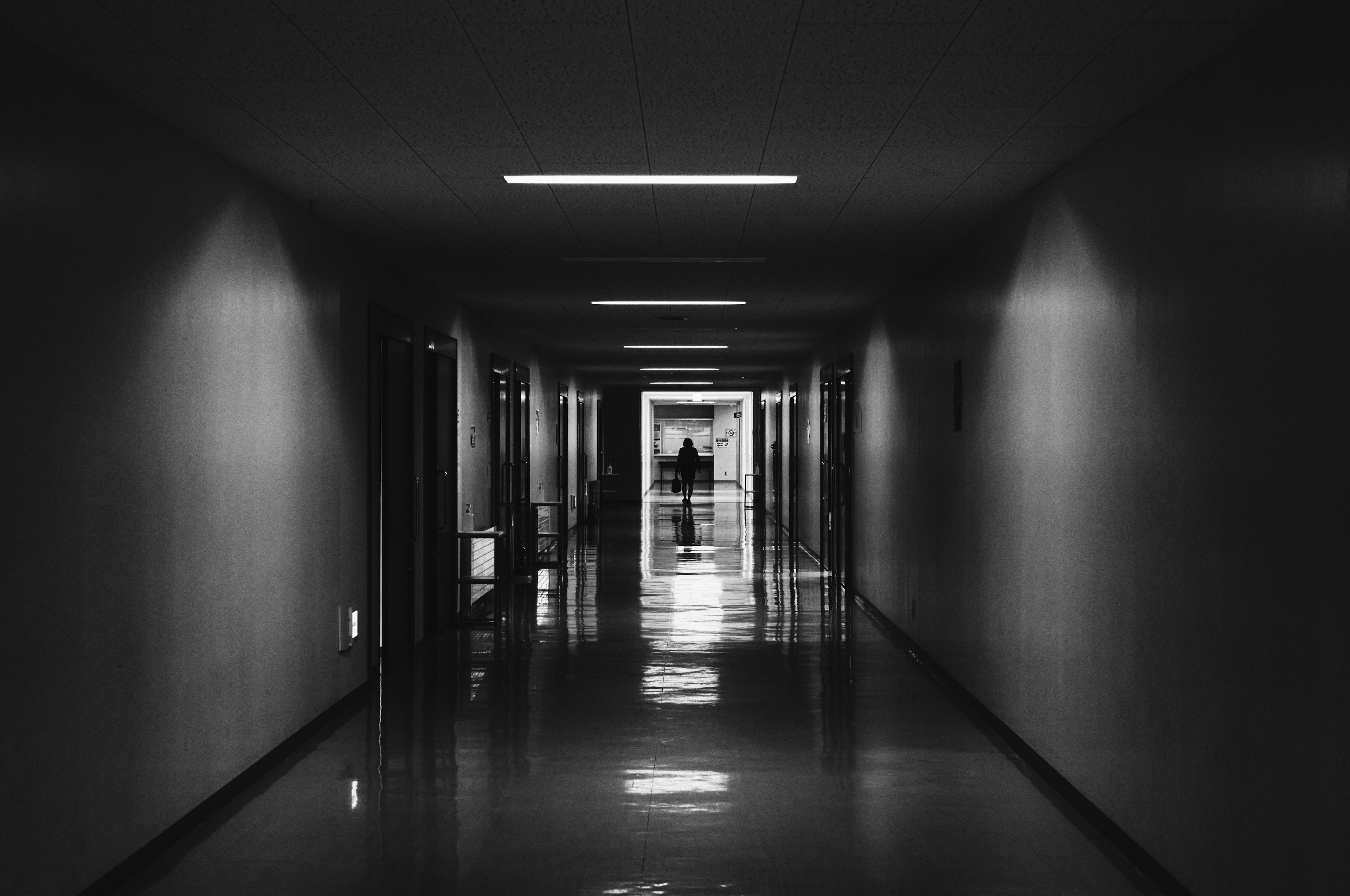 Dark corridor with bright exit in the distance and reflective floor