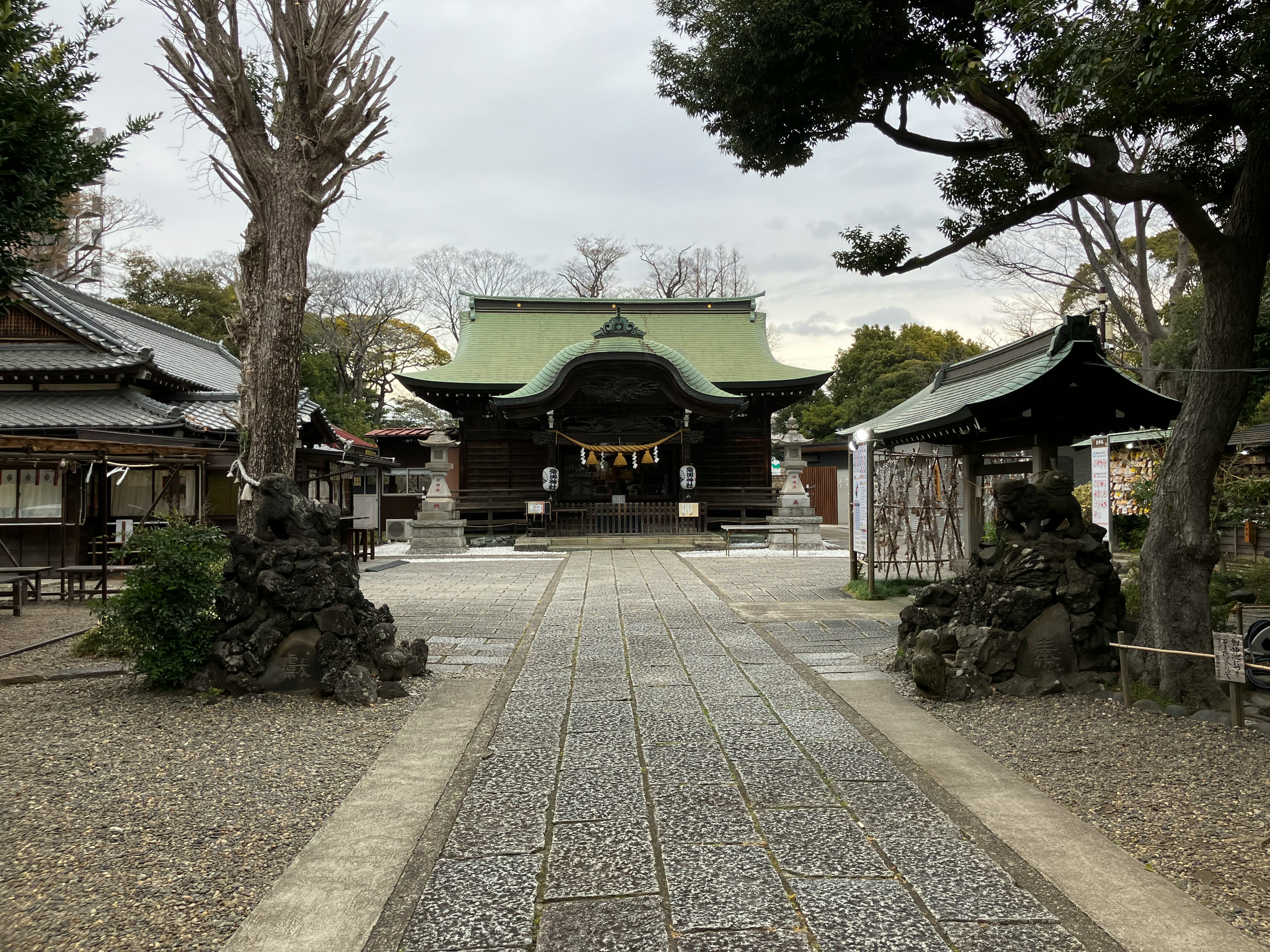 静かな神社の境内に続く石畳の小道と緑色の屋根の本殿