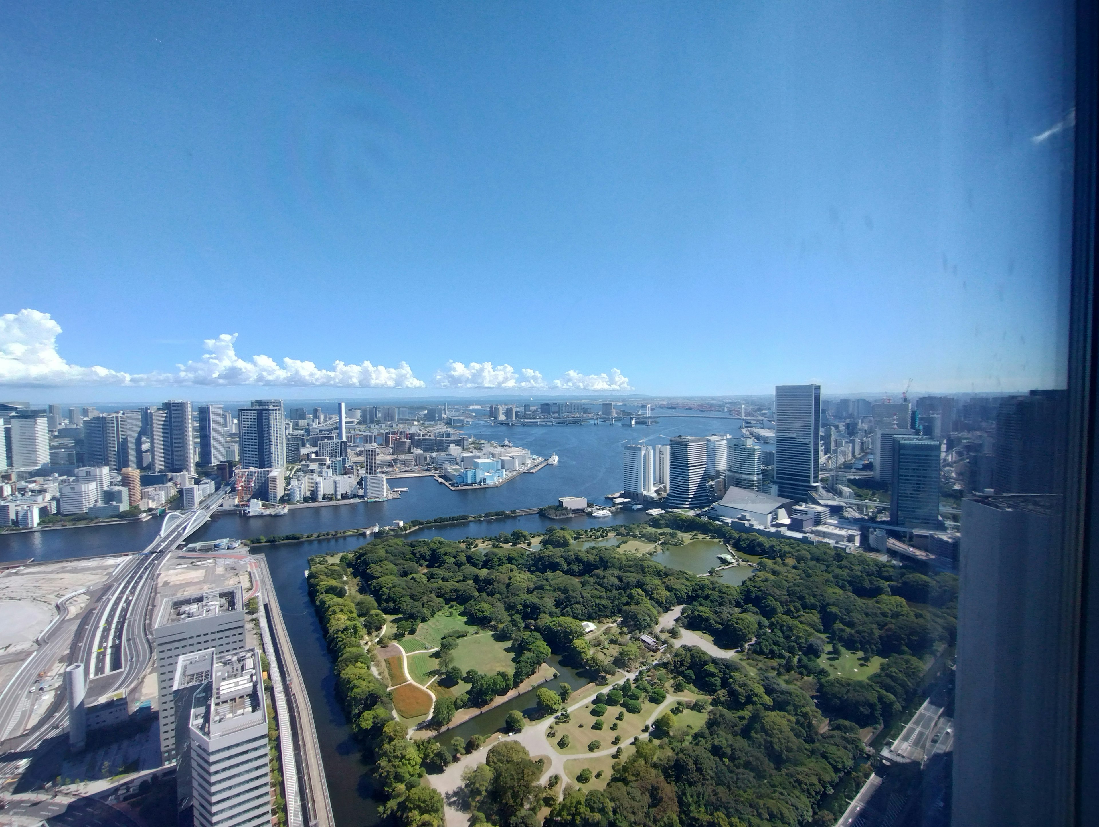 Pemandangan garis langit Tokyo dari gedung tinggi dengan langit biru, air, taman hijau, lanskap perkotaan