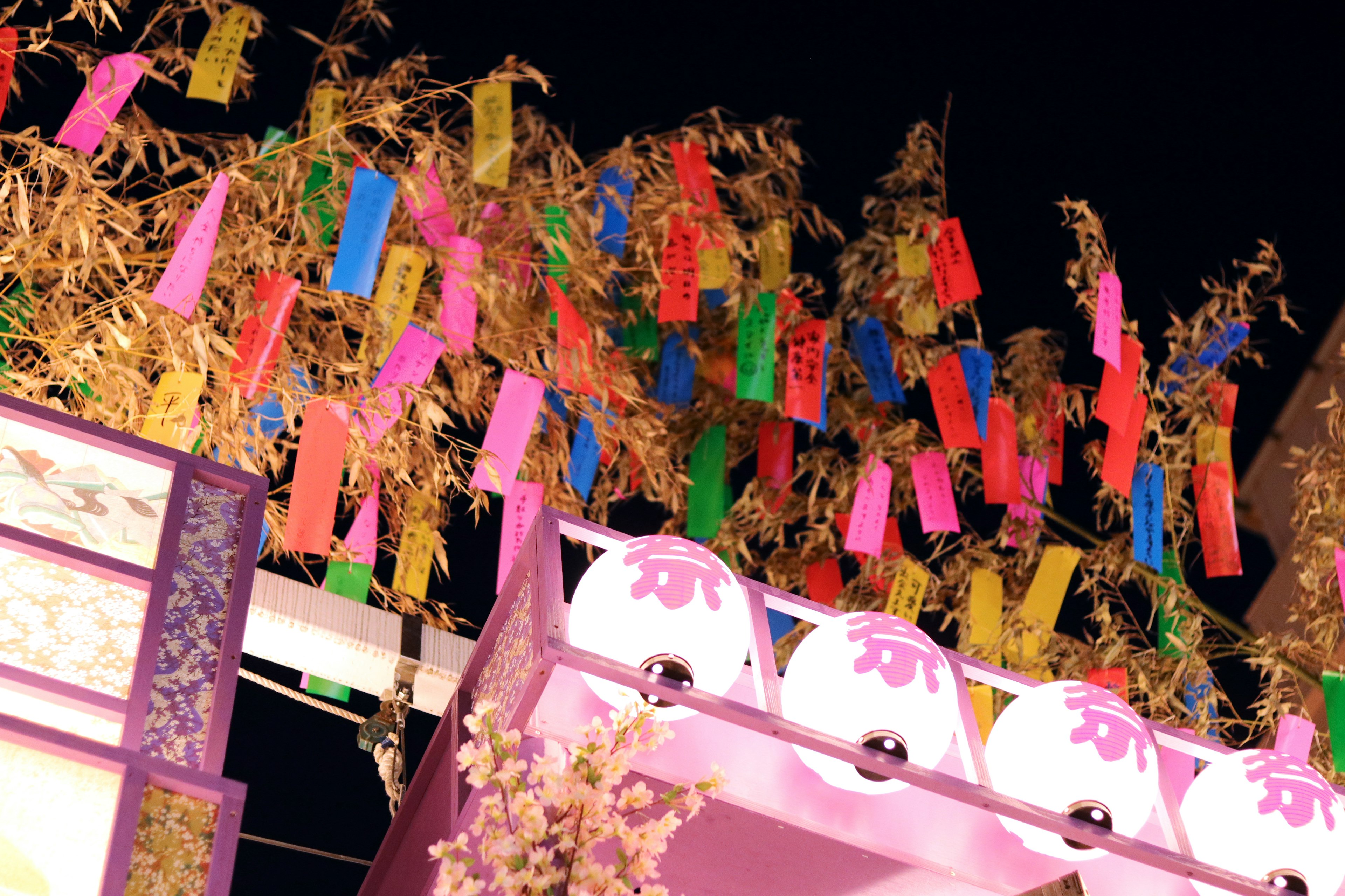 Bandes de papier colorées suspendues à des branches de bambou sur fond de nuit