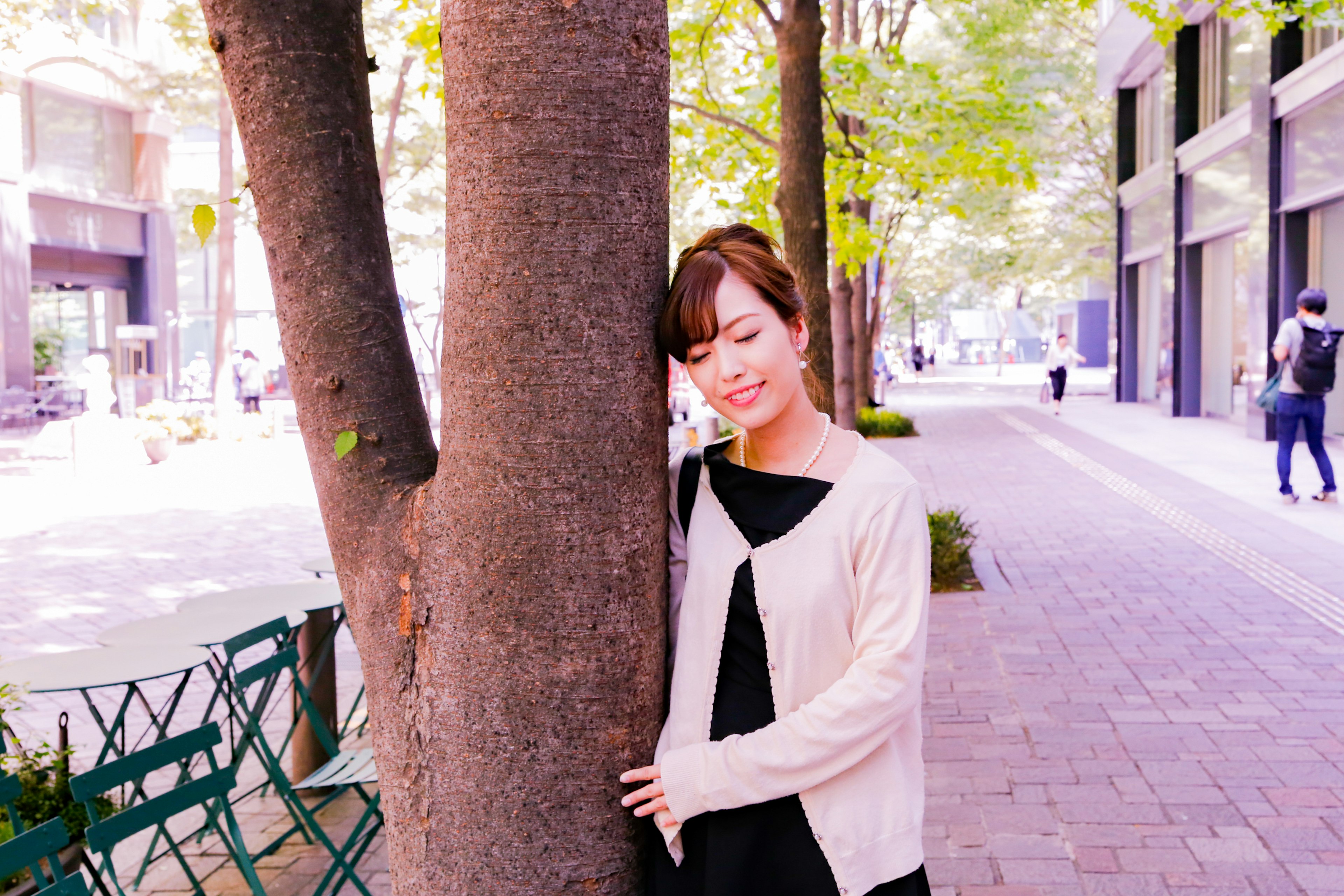 A woman leaning against a tree in an urban setting