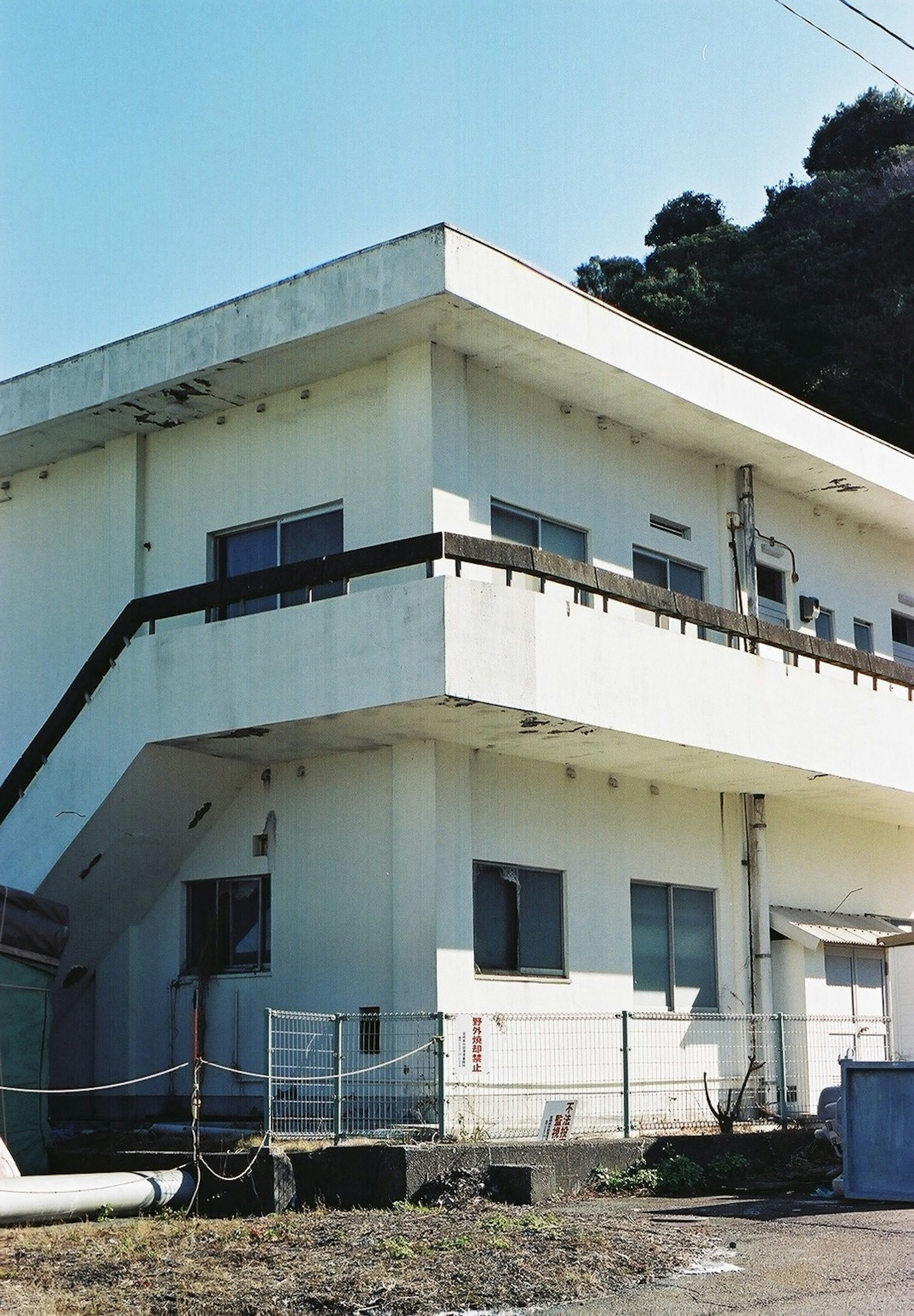 Edificio blanco de dos pisos con escalera visible