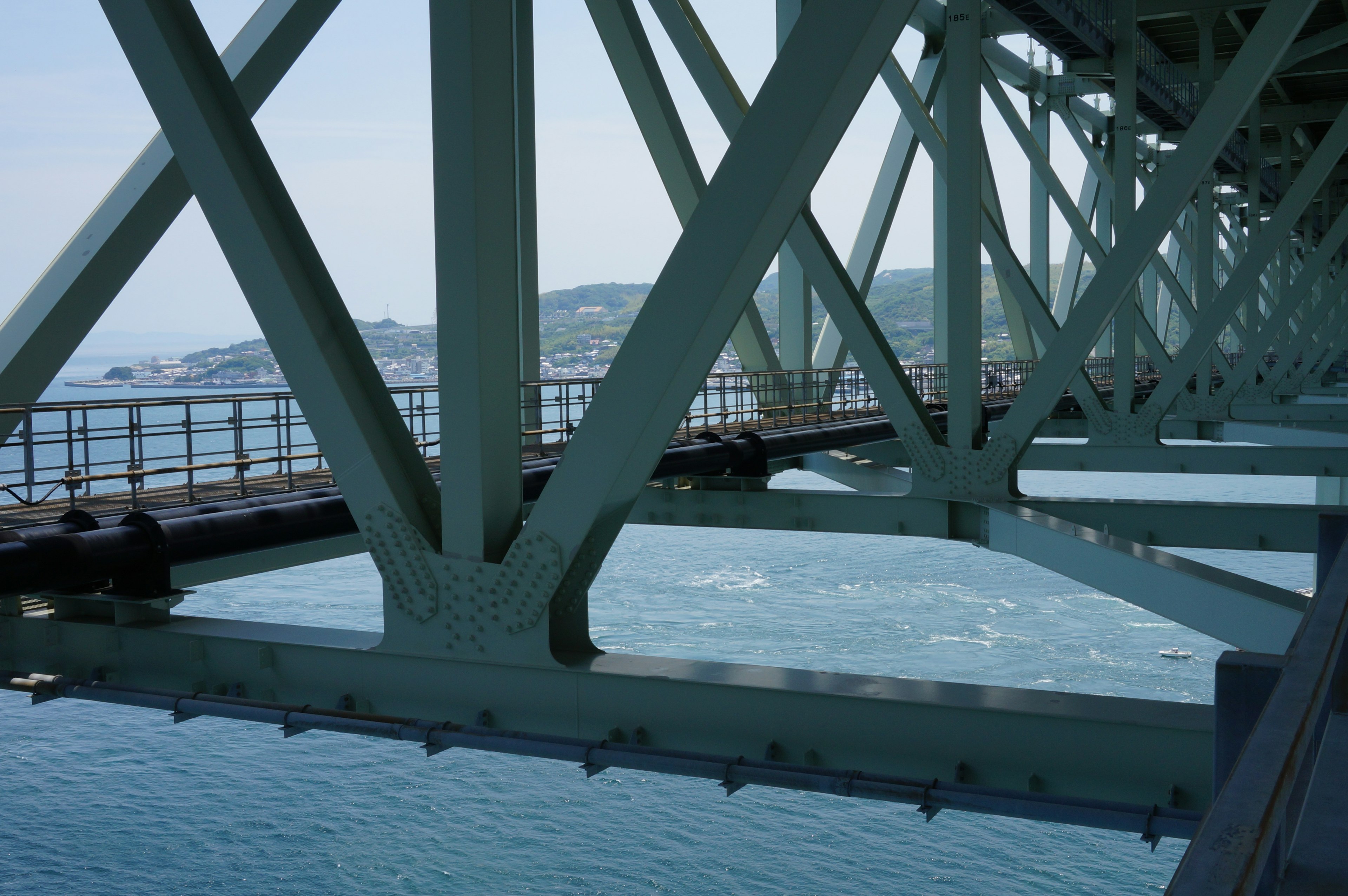 Pemandangan struktur jembatan logam hijau di atas lautan