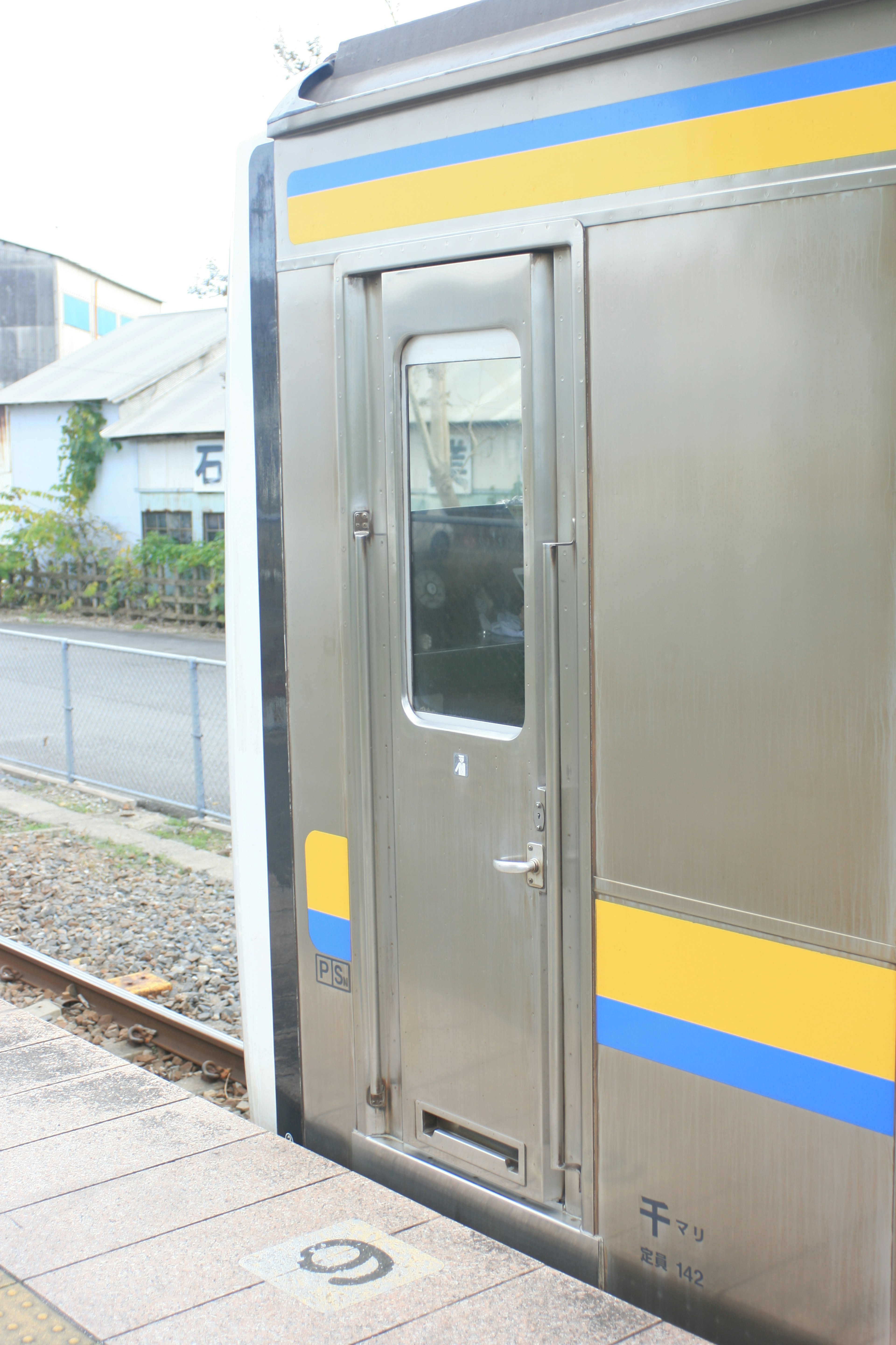 Acercamiento a una puerta de tren con ventana Exterior metálico plateado con una franja azul