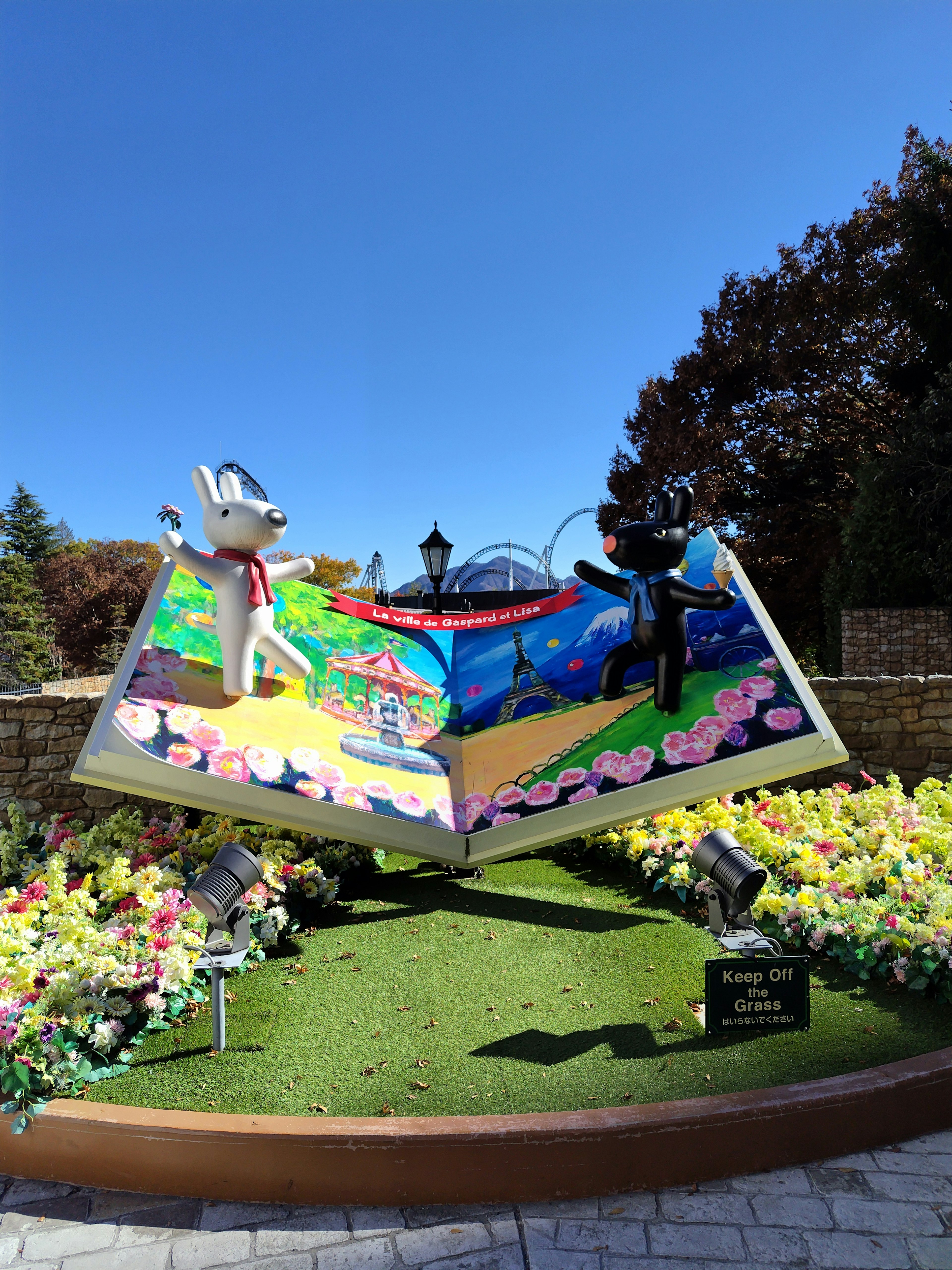 Grande scultura di un libro con fiori colorati e cielo blu