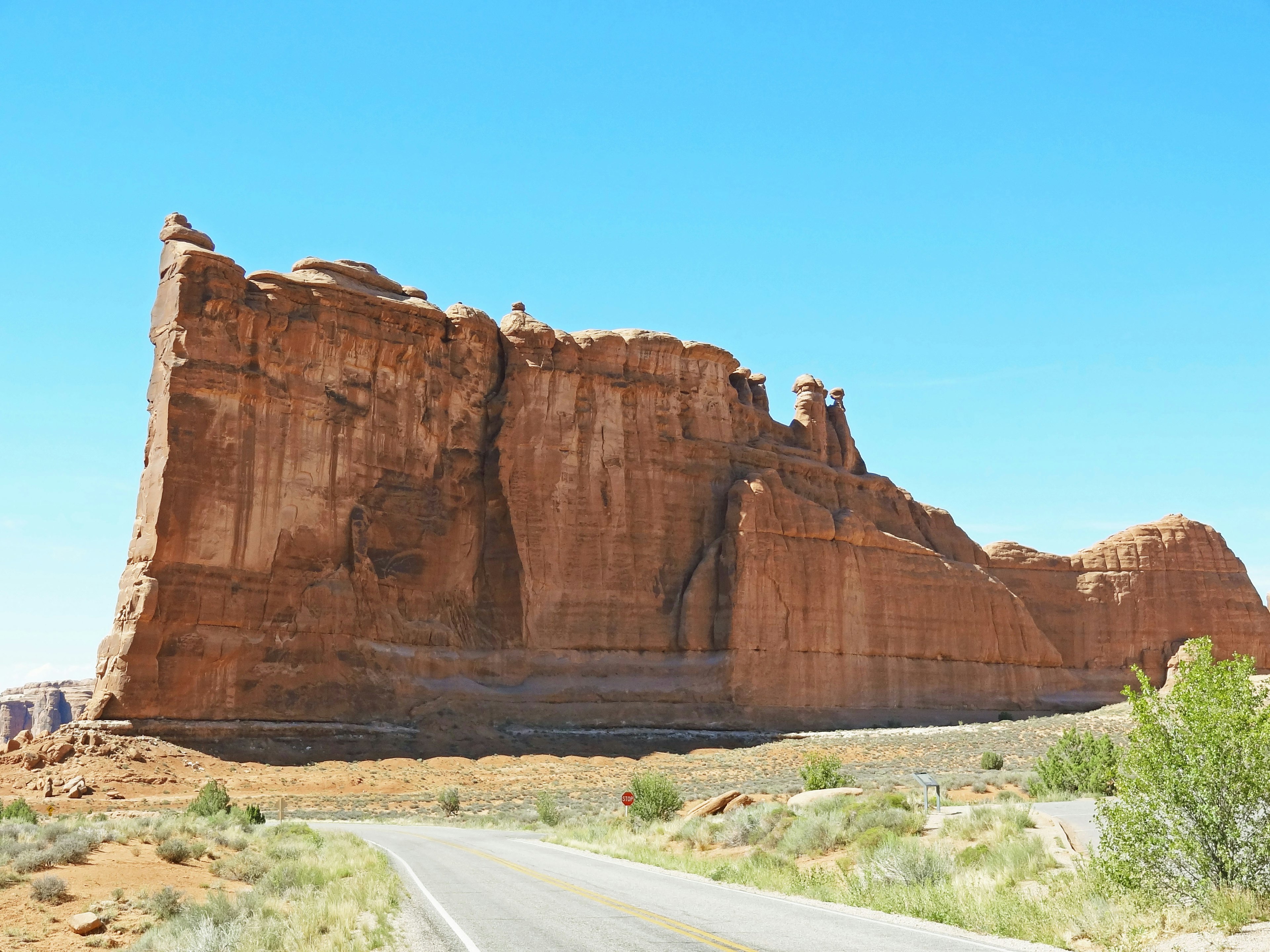 Une falaise rouge imposante sous un ciel bleu clair avec une route