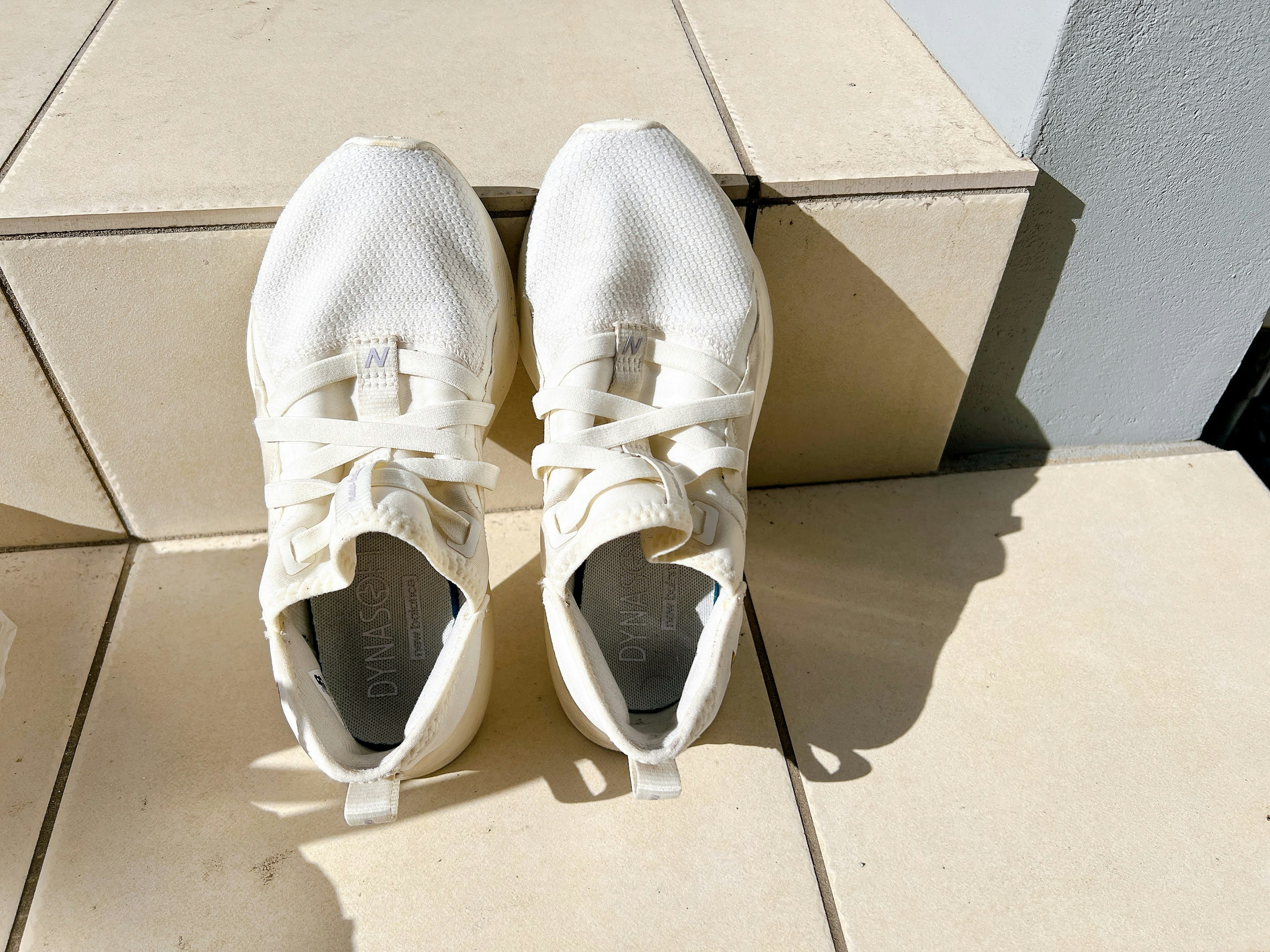 White sneakers placed on tiled surface