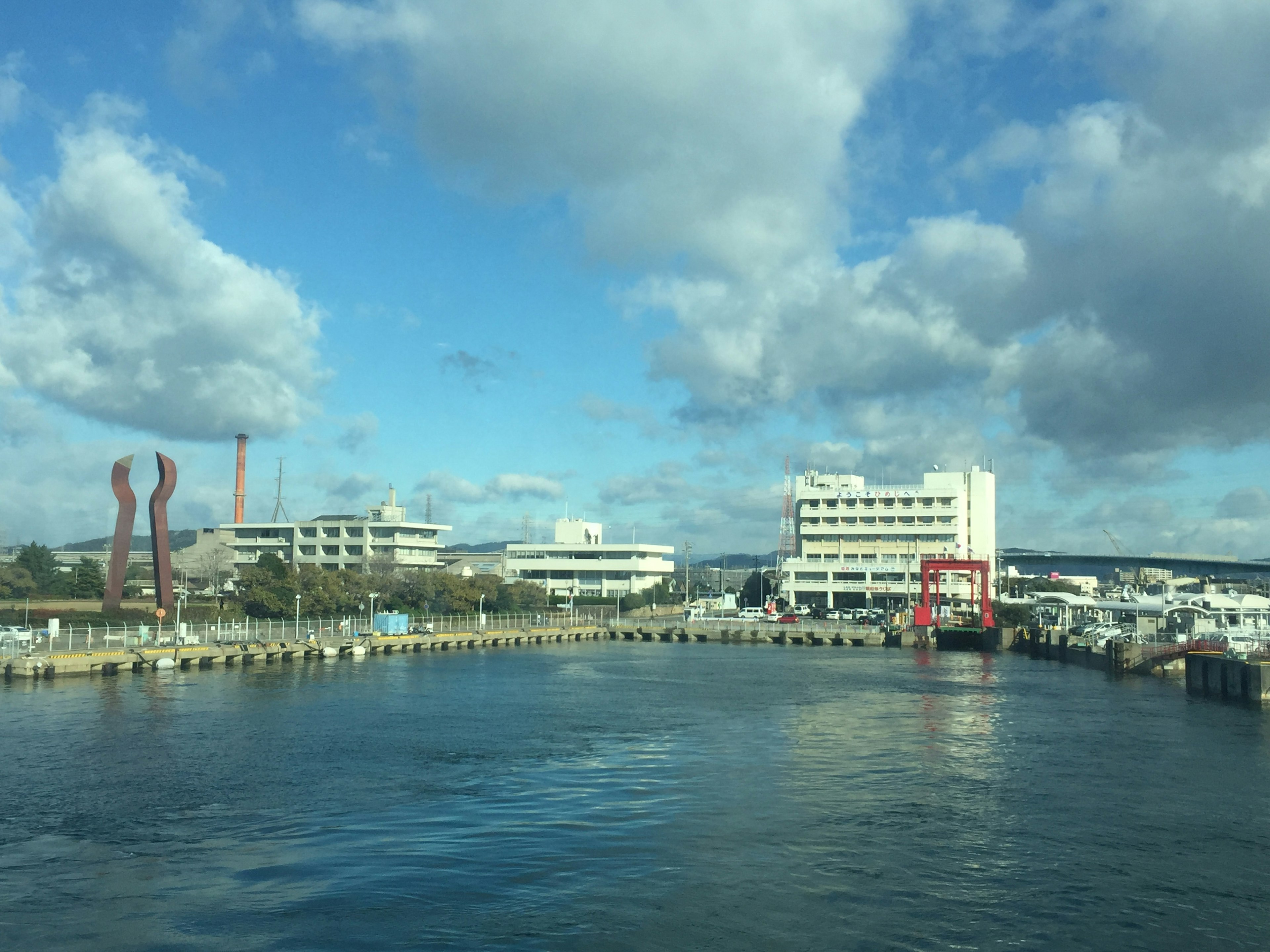 Harbor view with buildings and sculptures under a blue sky