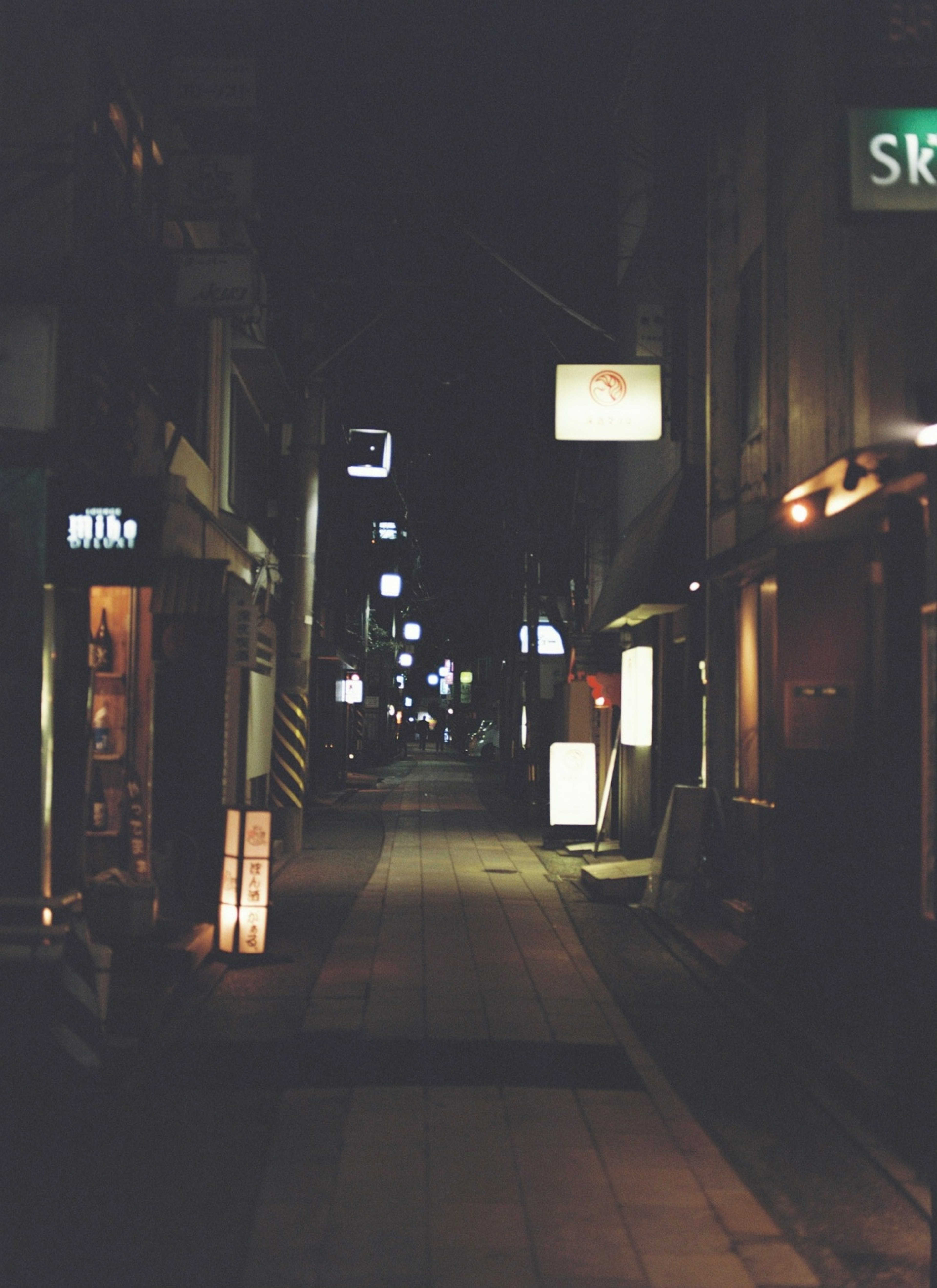 夜晚寧靜街道的場景，街邊有燈光招牌和店舖