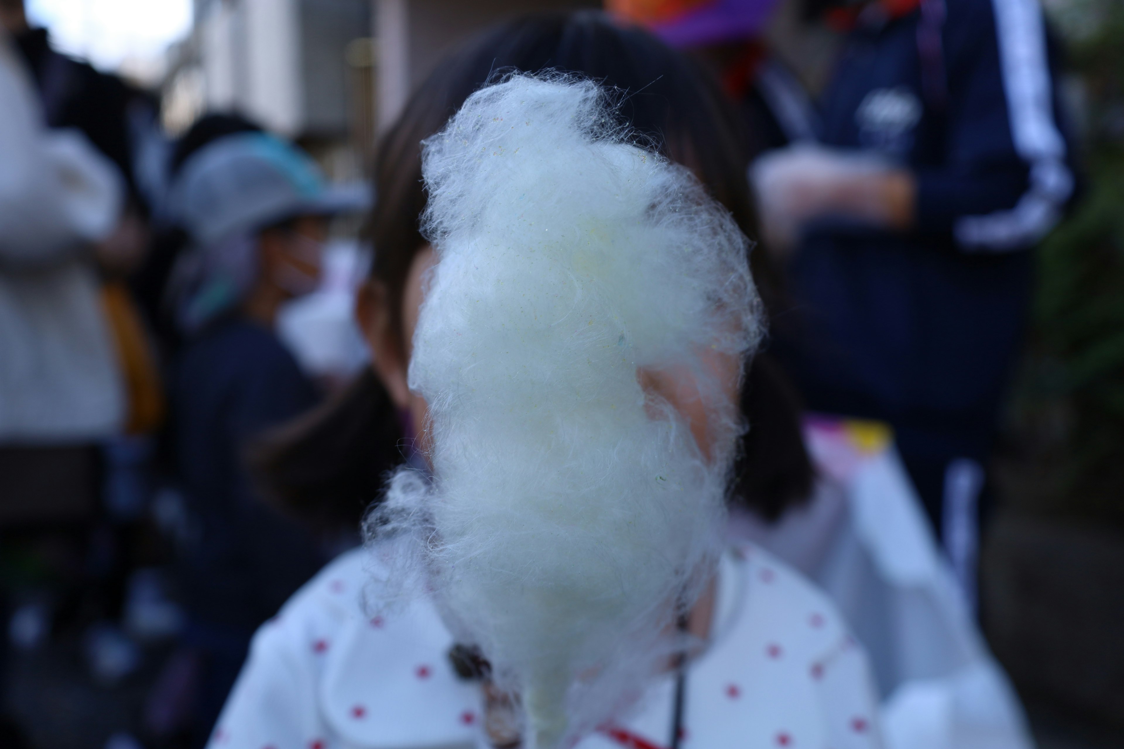 Child holding cotton candy obscuring their face