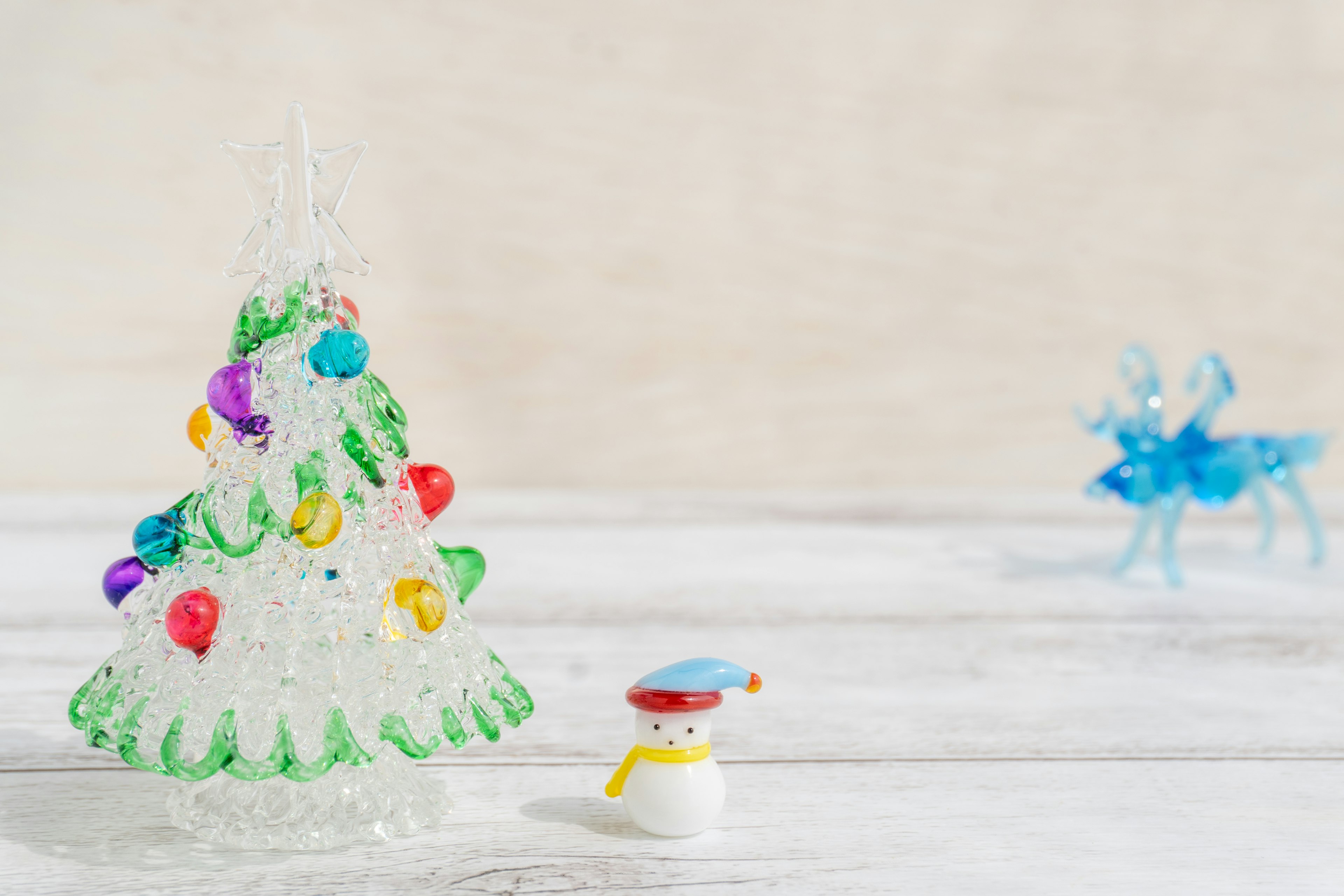 Decorative transparent Christmas tree with colorful lights and a snowman figurine