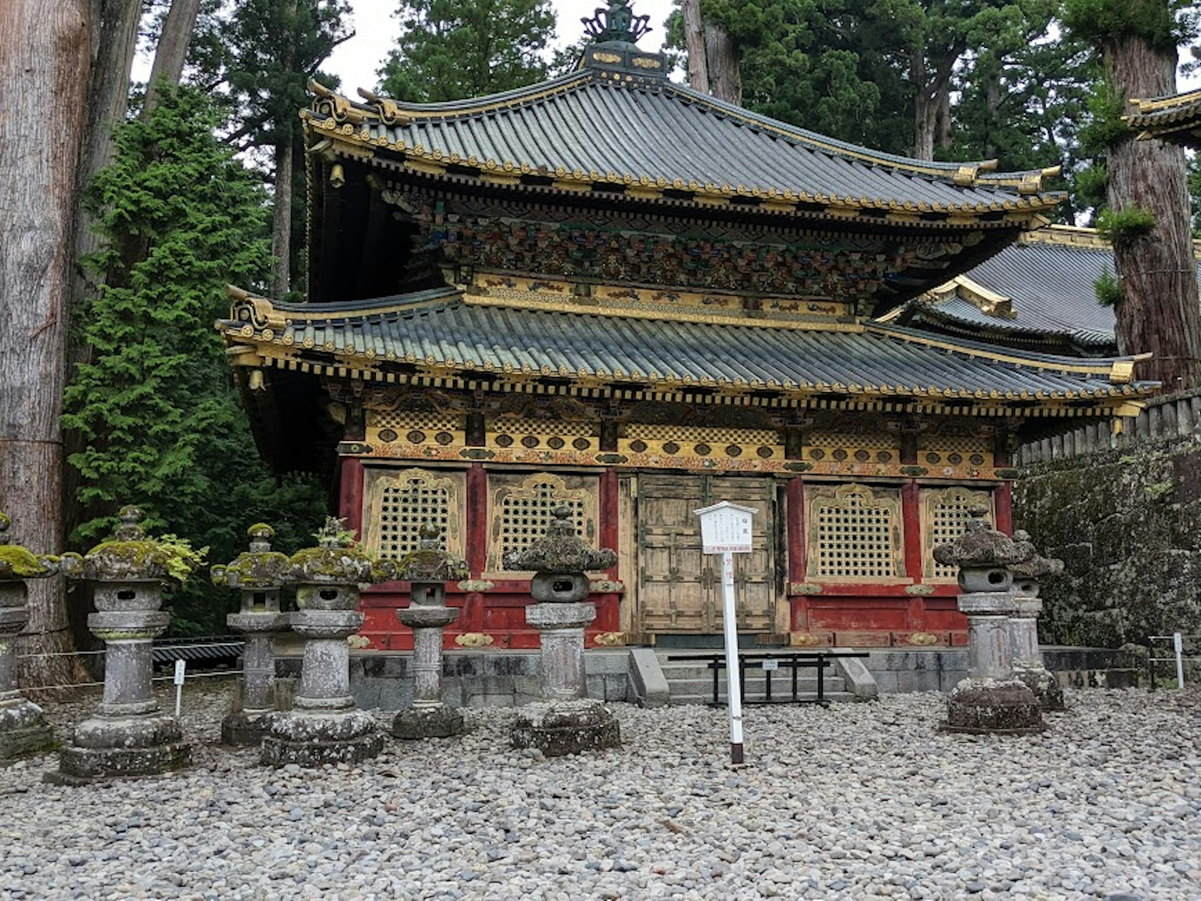 A beautifully decorated shrine building surrounded by stone lanterns