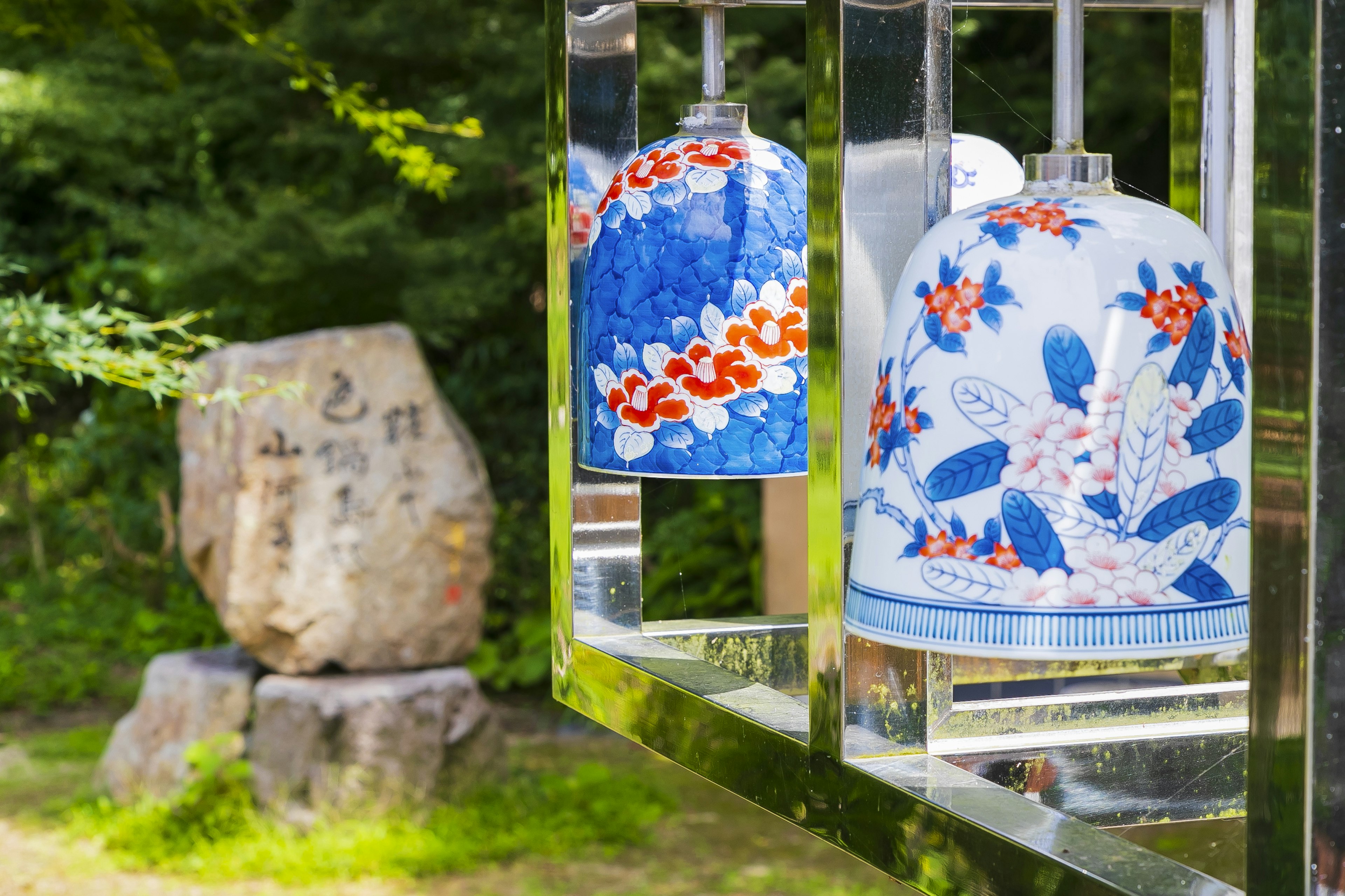 Campane a vento floreali blu e scultura in pietra in un ambiente naturale