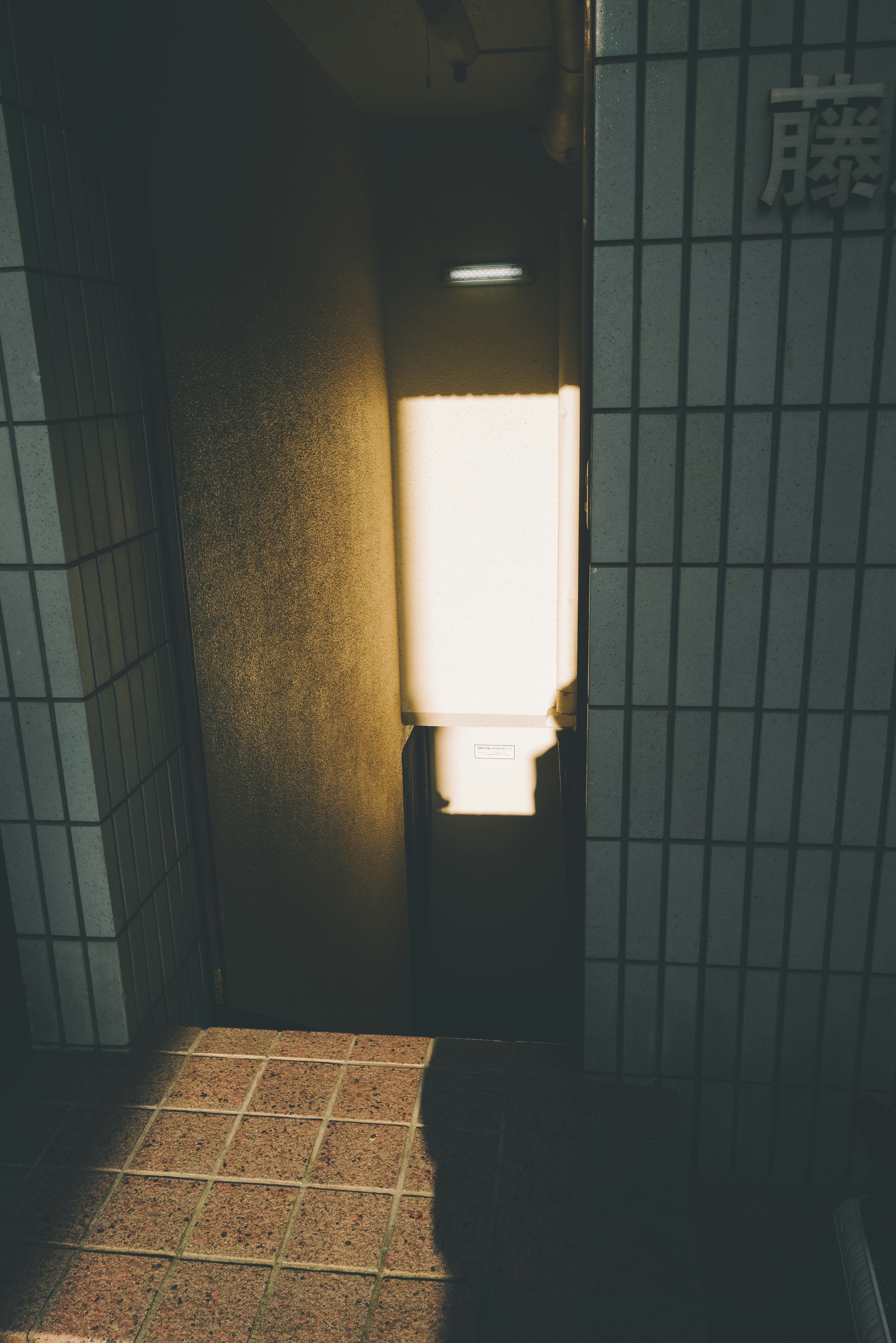 Bright restroom entrance with tiled walls and floor visible