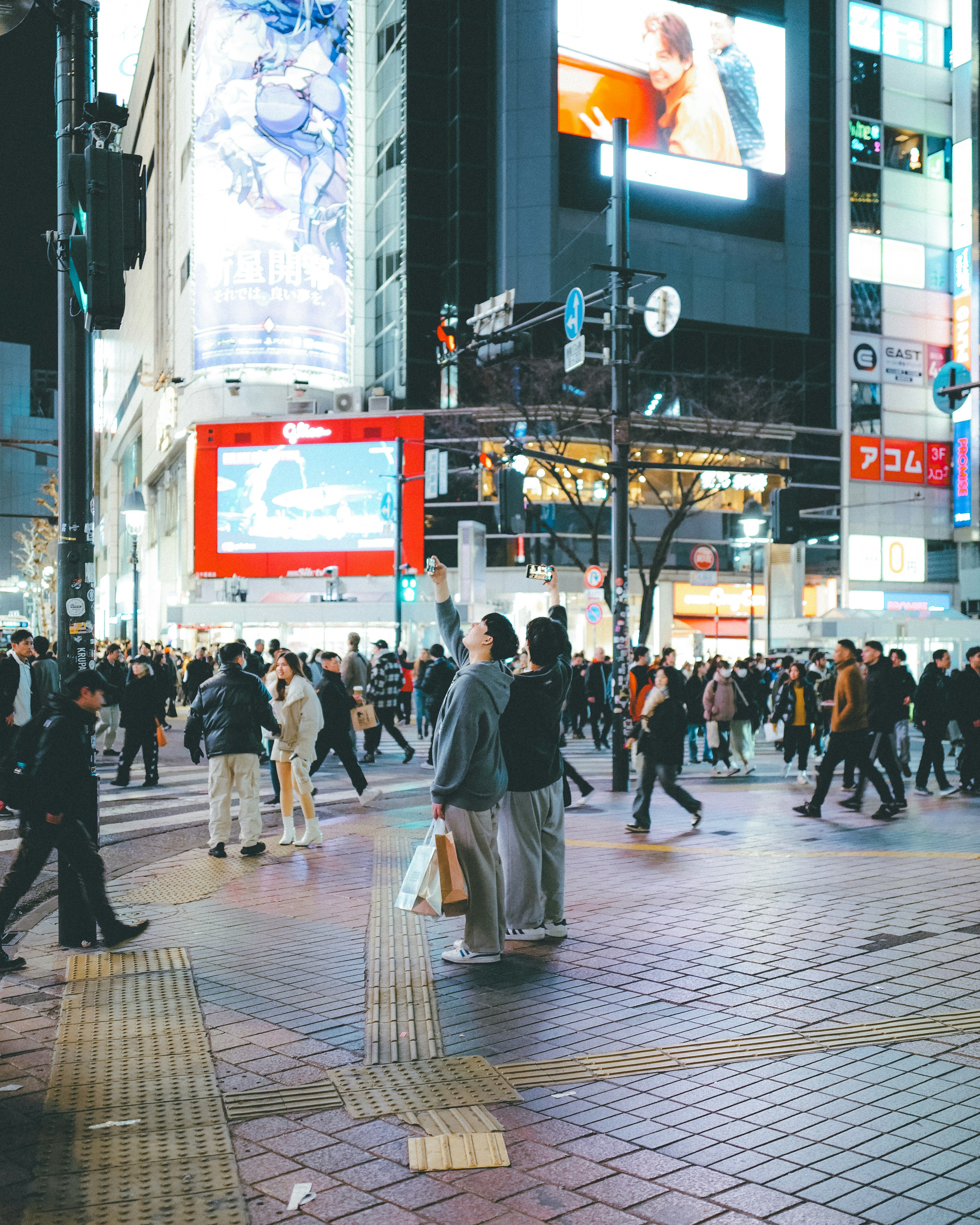 Passage animé de Shibuya avec de nombreux piétons et des publicités lumineuses