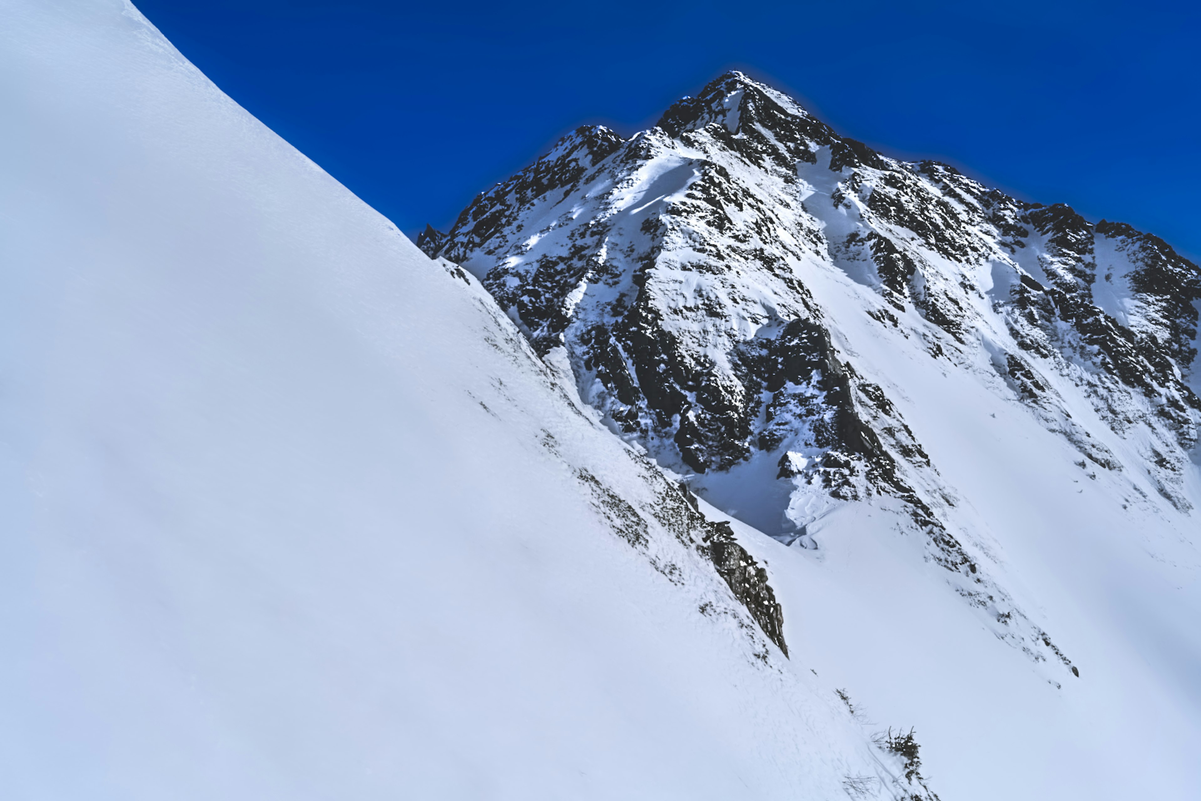 Schneebedeckter Berggipfel unter klarem blauen Himmel