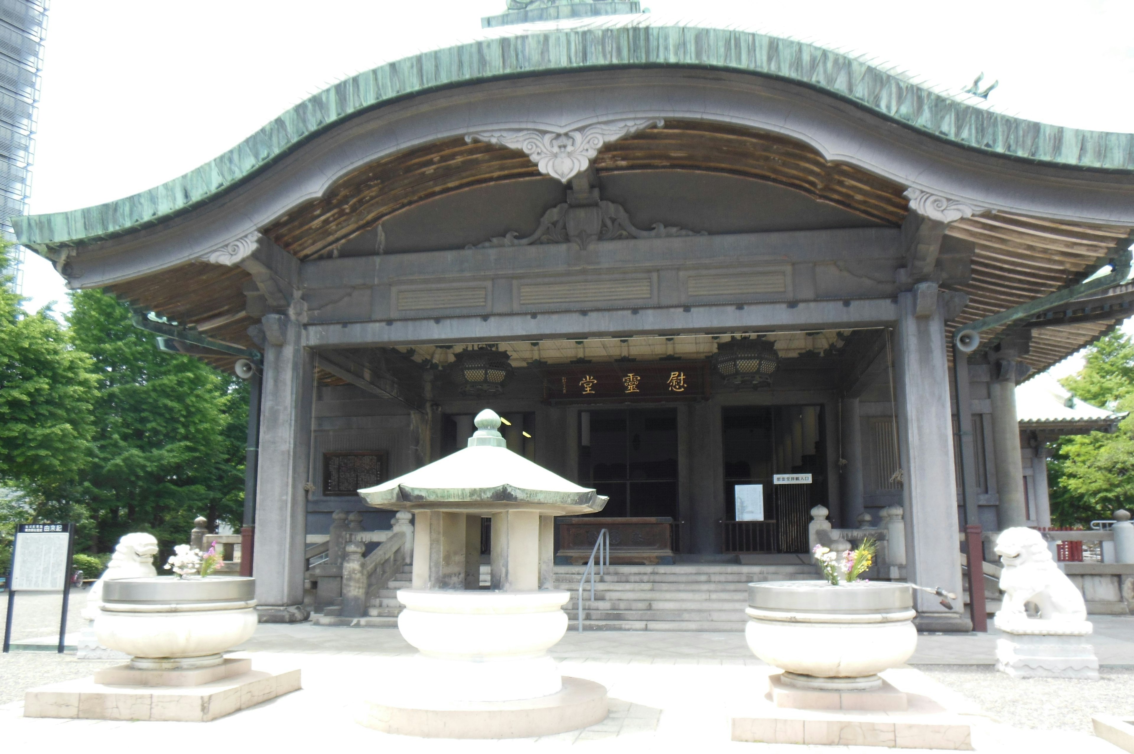 Traditional Japanese temple exterior with curved roof stone fountain and guardian lion statues