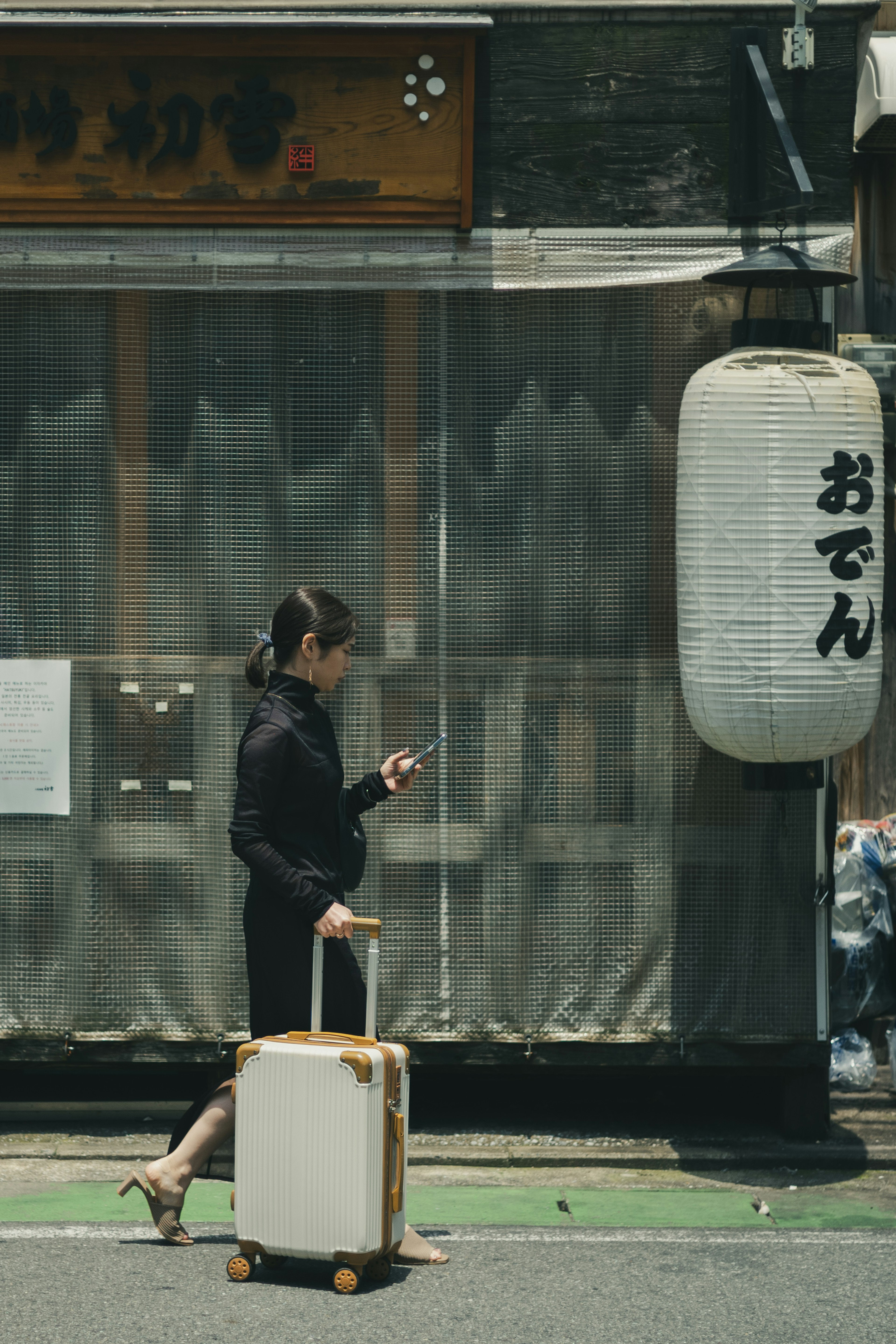 Una mujer caminando con una maleta frente a un restaurante japonés tradicional