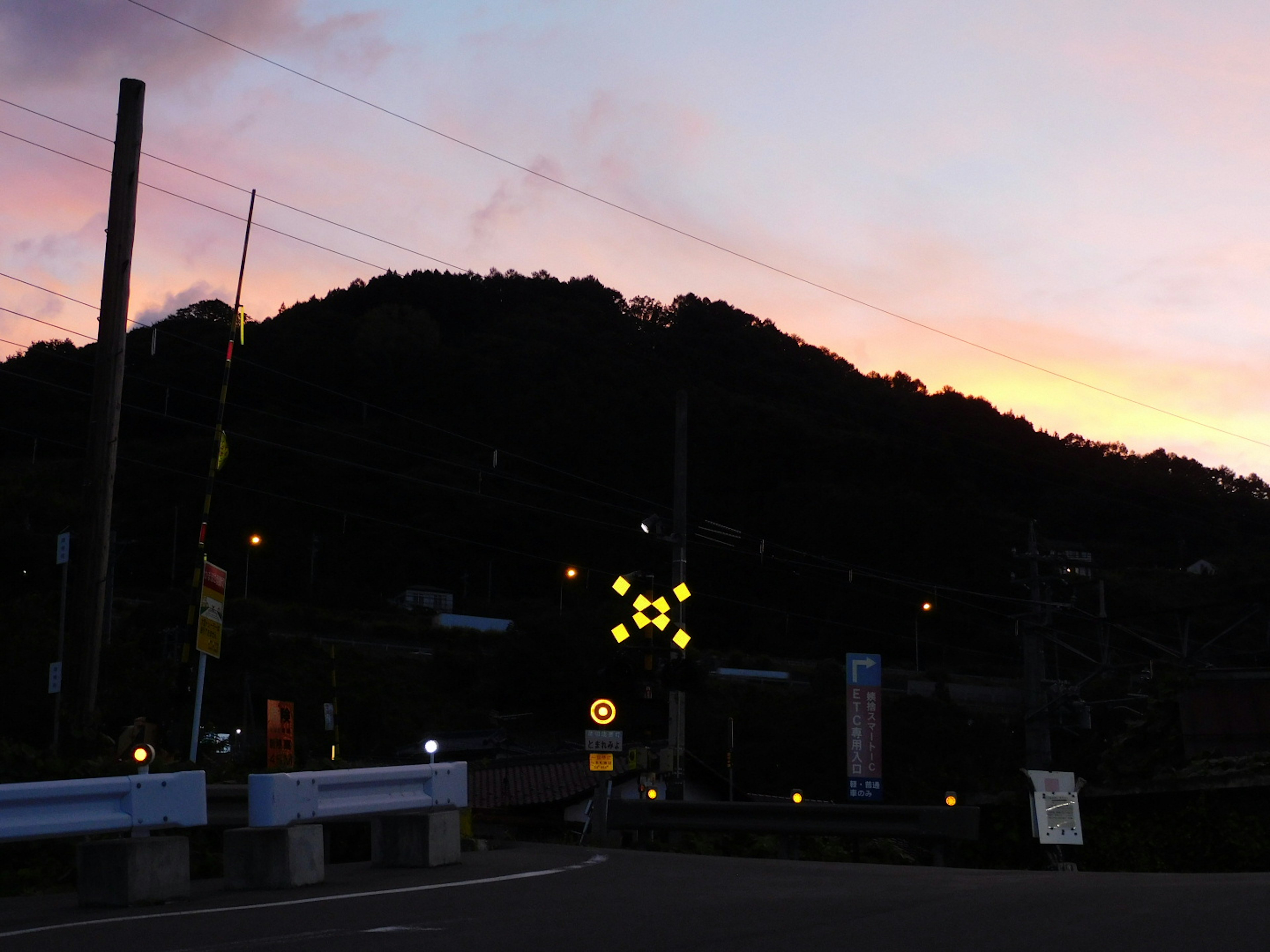 夕焼けの中、山がシルエットになり、街灯が輝く風景