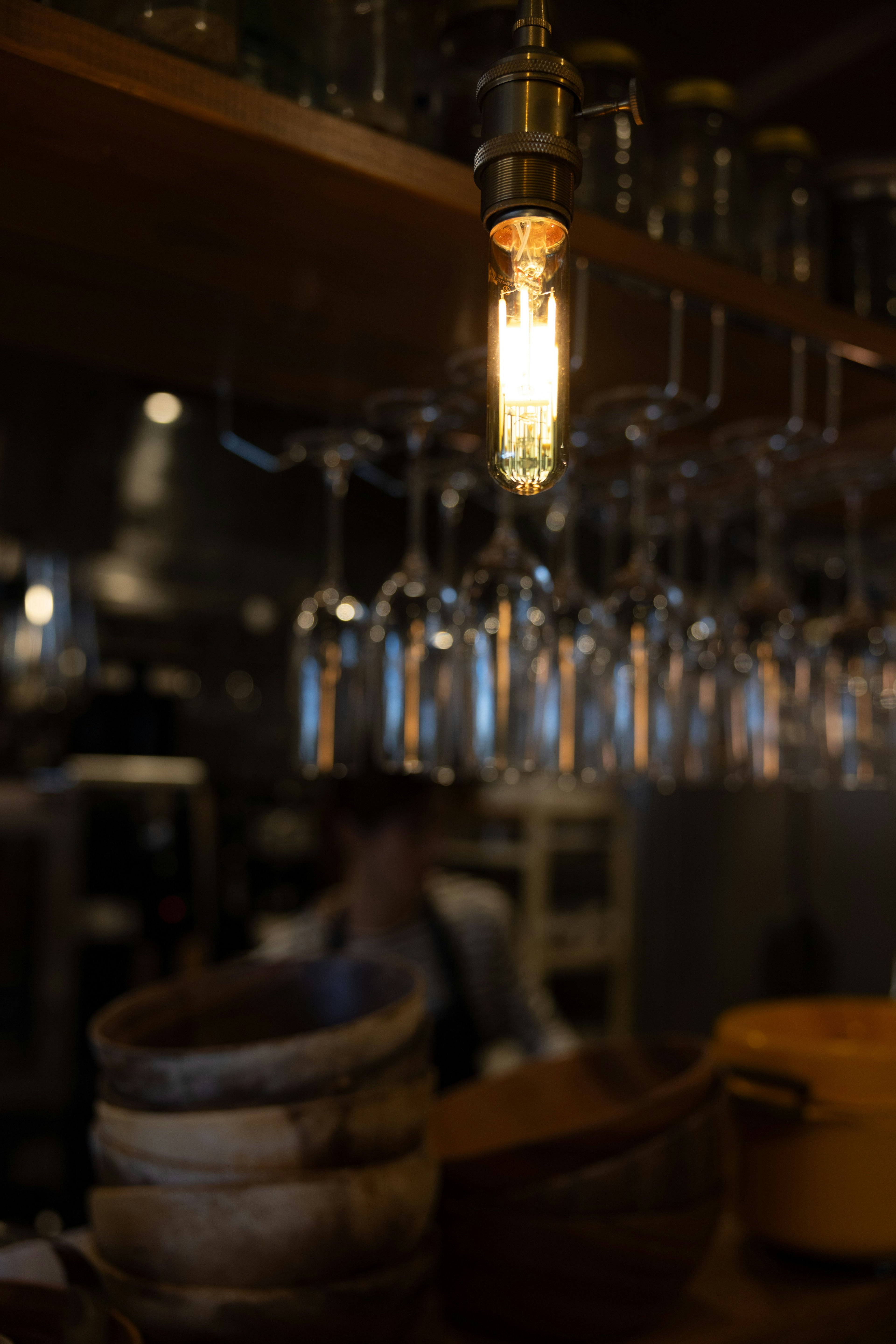 Innenansicht einer Bar mit einer hängenden Vintage-Glühbirne und Reihen von Gläsern