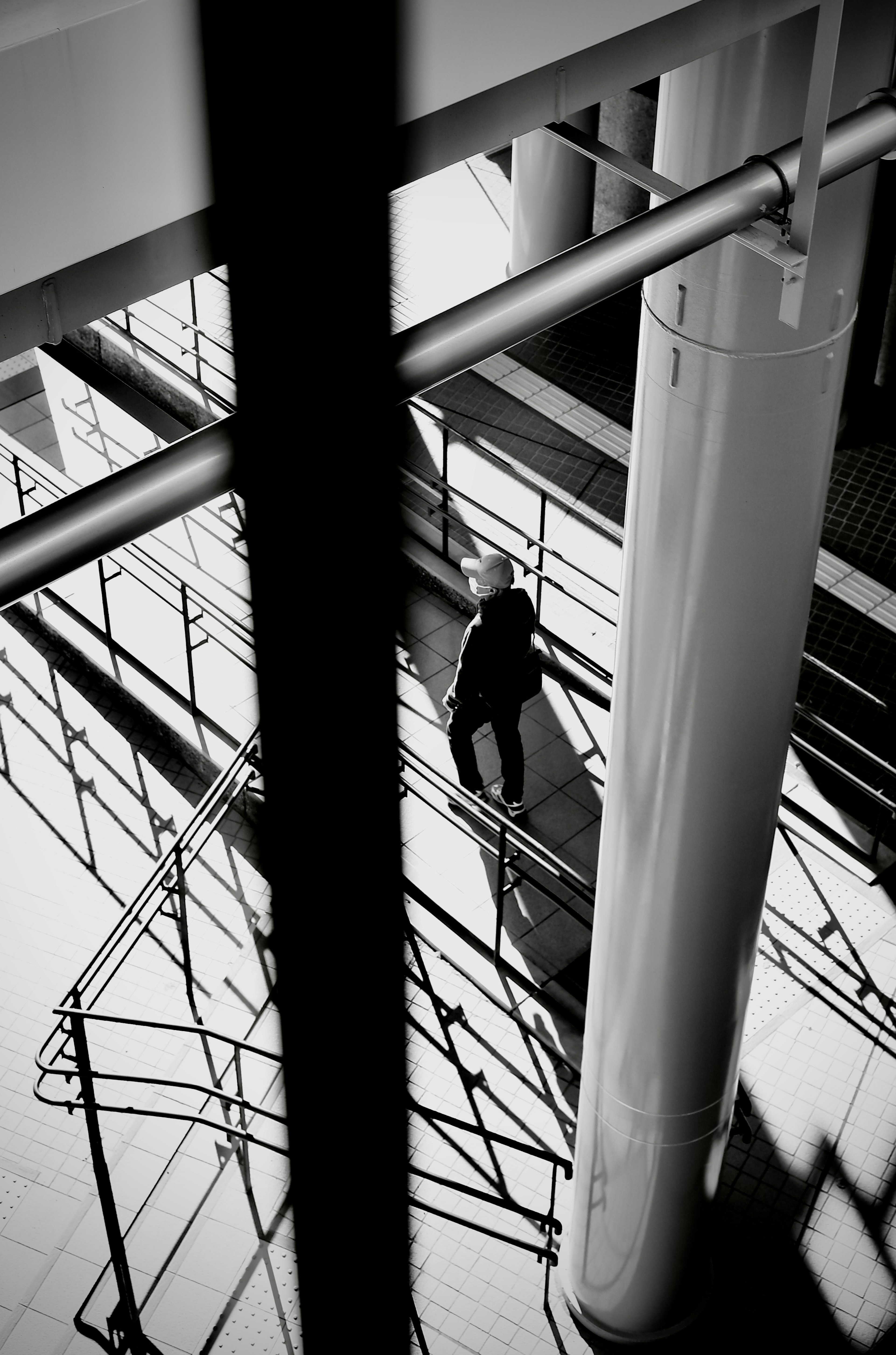 Figura en sombra caminando a través de un espacio arquitectónico moderno con líneas y sombras contrastantes