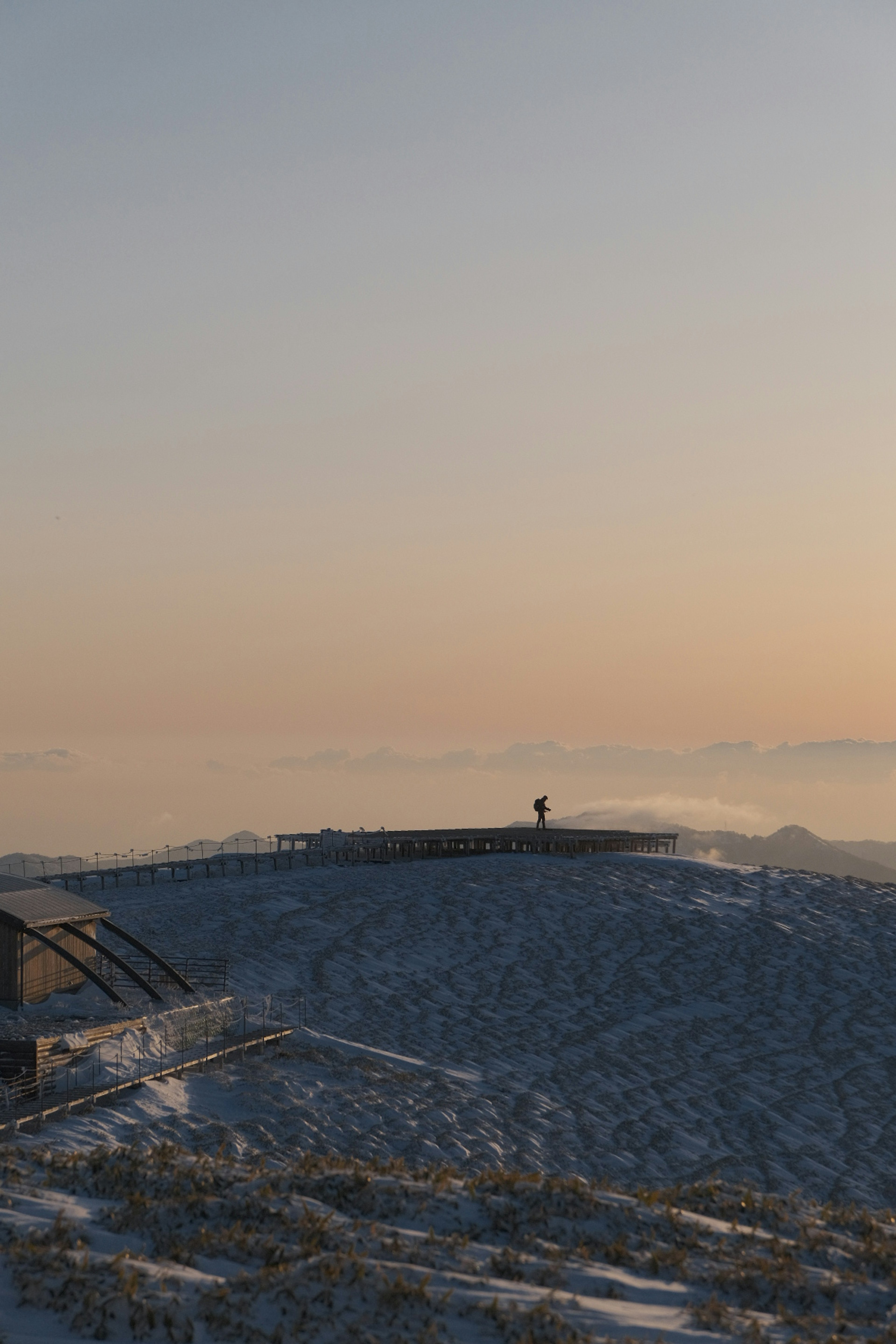 雪に覆われた山の頂上に立つ人と夕焼けの空